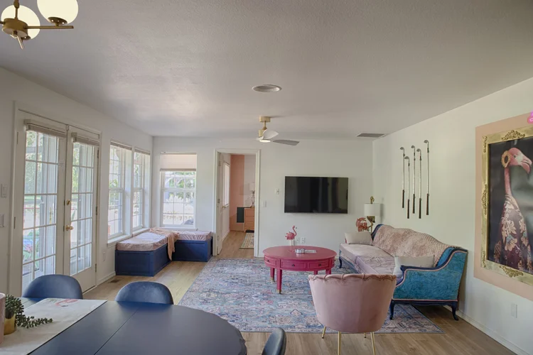 Living room with blue velvet sofa, golf club wall art, flamingo portrait and patterned rug