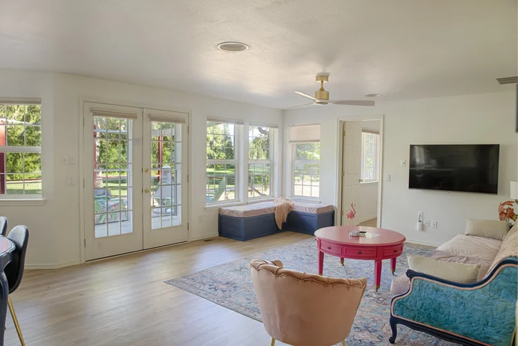 Bright living room with French doors, window bench seating, wall-mounted TV and pink coffee table