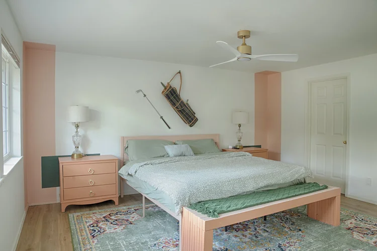 Bedroom with sage bedding, peach nightstands, bench at the foot of the bed and vintage golf decor