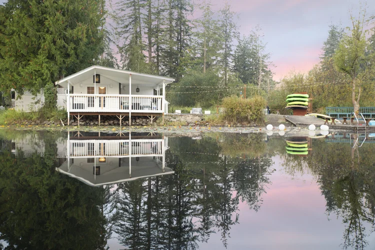 Lakeside Wonderland cottage and kayak rack reflected in a still Graham lake at dusk