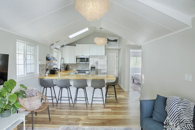 Vaulted great room with skylight, butcher block peninsula, gray bar stools and stainless appliances