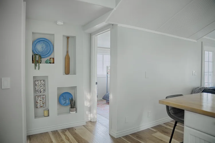 Hallway with recessed wall niches holding blue plates, a wooden paddle and small plants