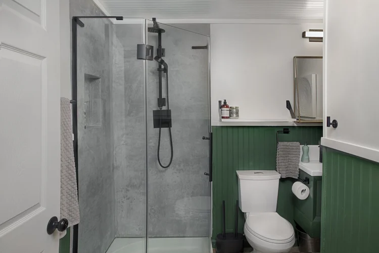 Bathroom with glass walk-in shower, black fixtures and green beadboard wainscoting