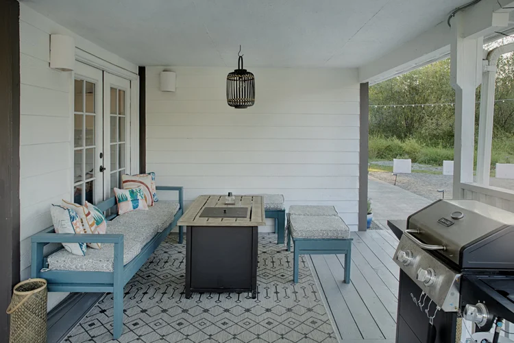 Covered patio with blue benches, gas fire table, lantern pendant and stainless grill