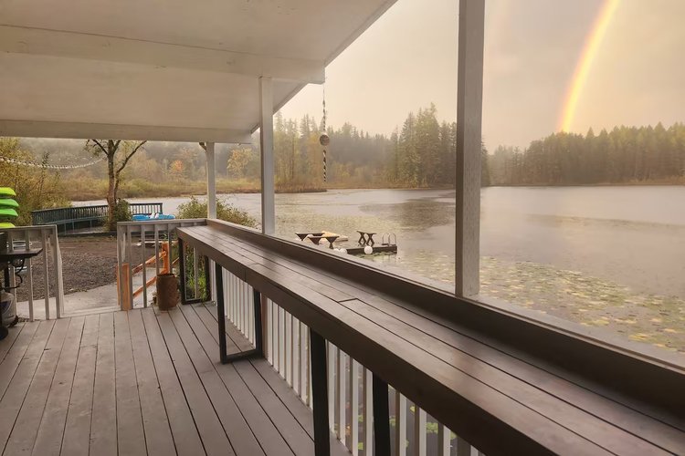 Rainbow over the misty lake, seen from the covered deck with its long wood bar ledge