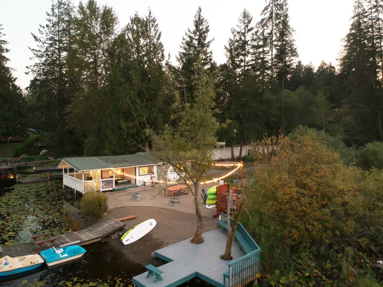 Aerial view of Lakeside Wonderland at dusk with cottage, string-lit yard, docks and boats