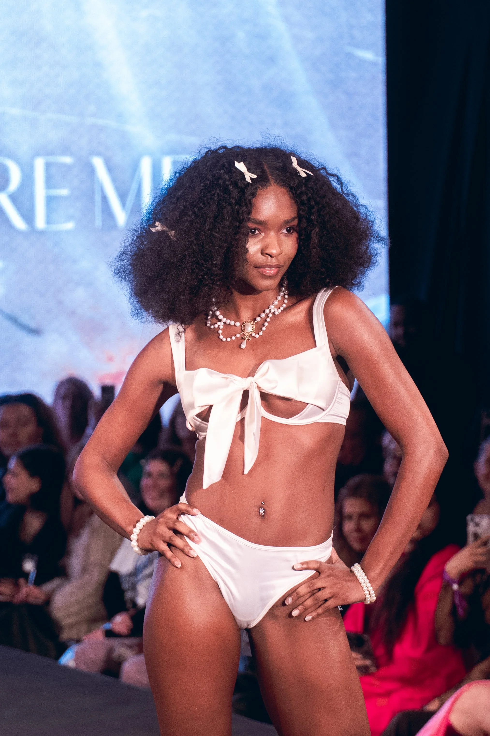 Curly-haired model in white lingerie poses on the Adore Me runway at New York Fashion Week 2024