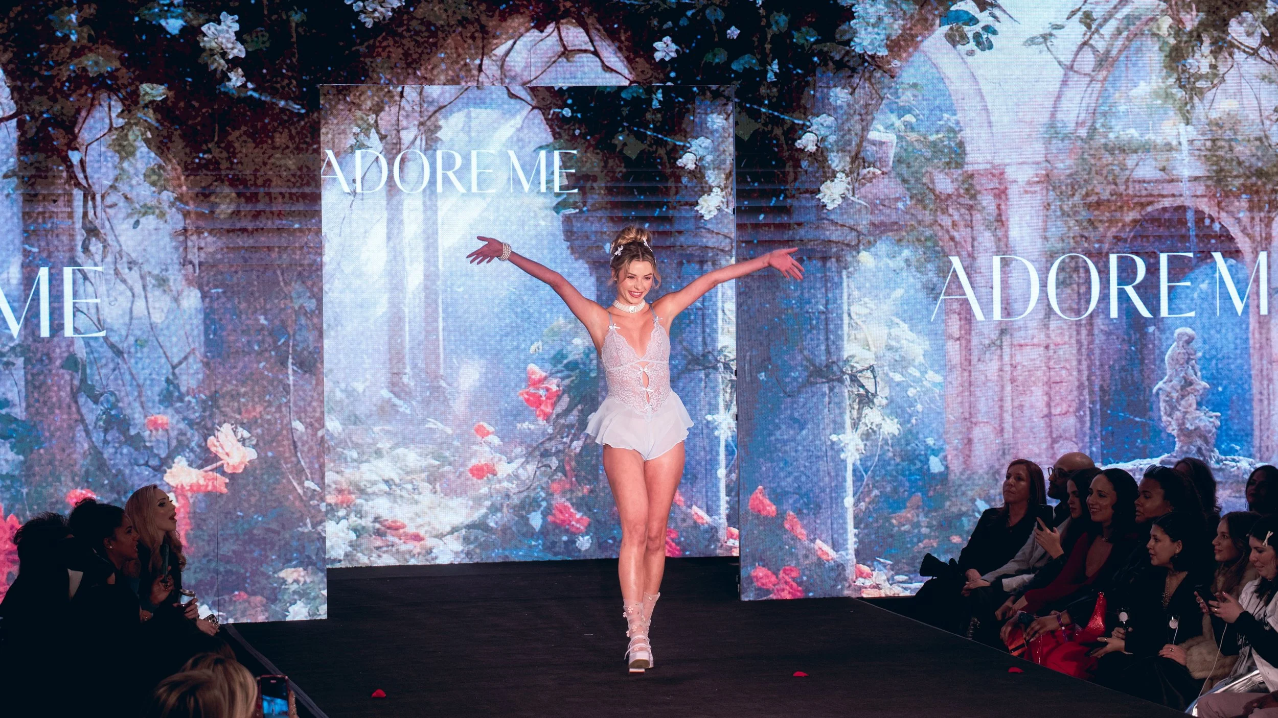 Model in a pale blue outfit extends her arms on the Adore Me runway at New York Fashion Week 2024