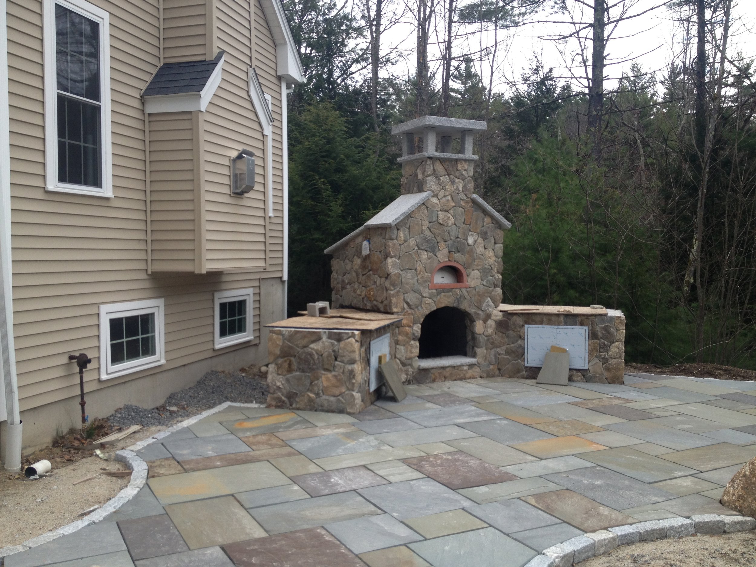 Professional landscape design with an outdoor fireplace in Waltham, MA.