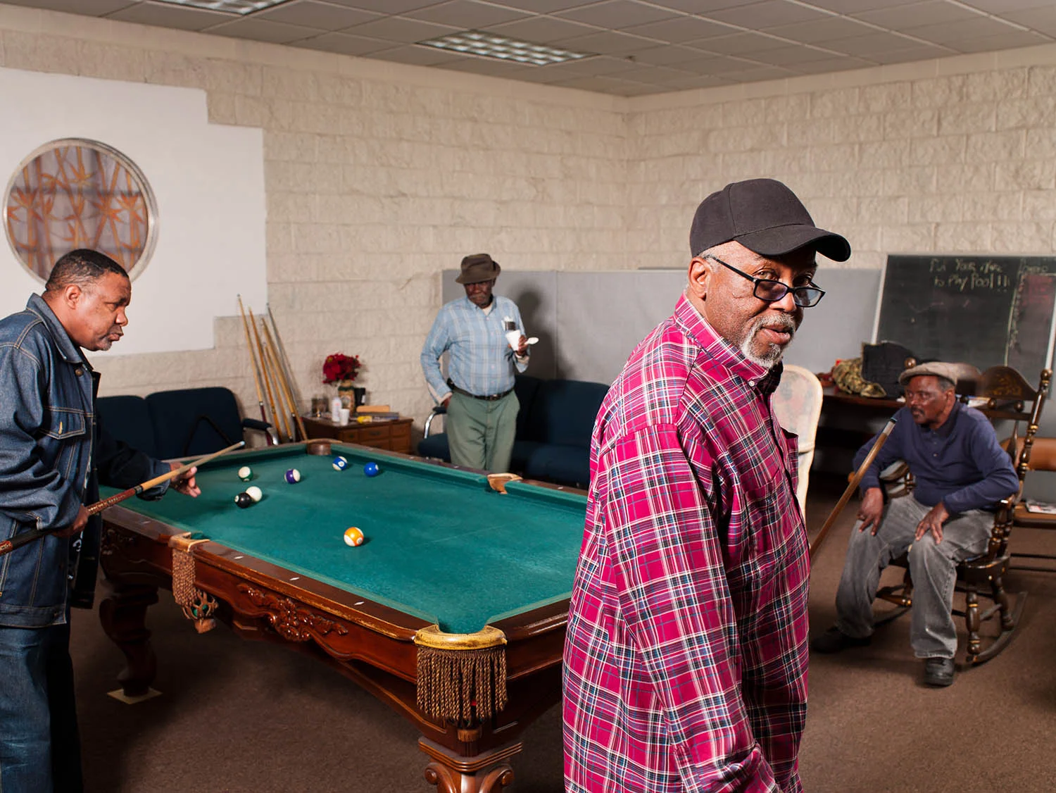 Jun Bradley (in plaid) and Donald Lewis shoot pool while John Pierce and Lloyd Johnson look on at the Lindsay Senior Center on March 14, 2012.