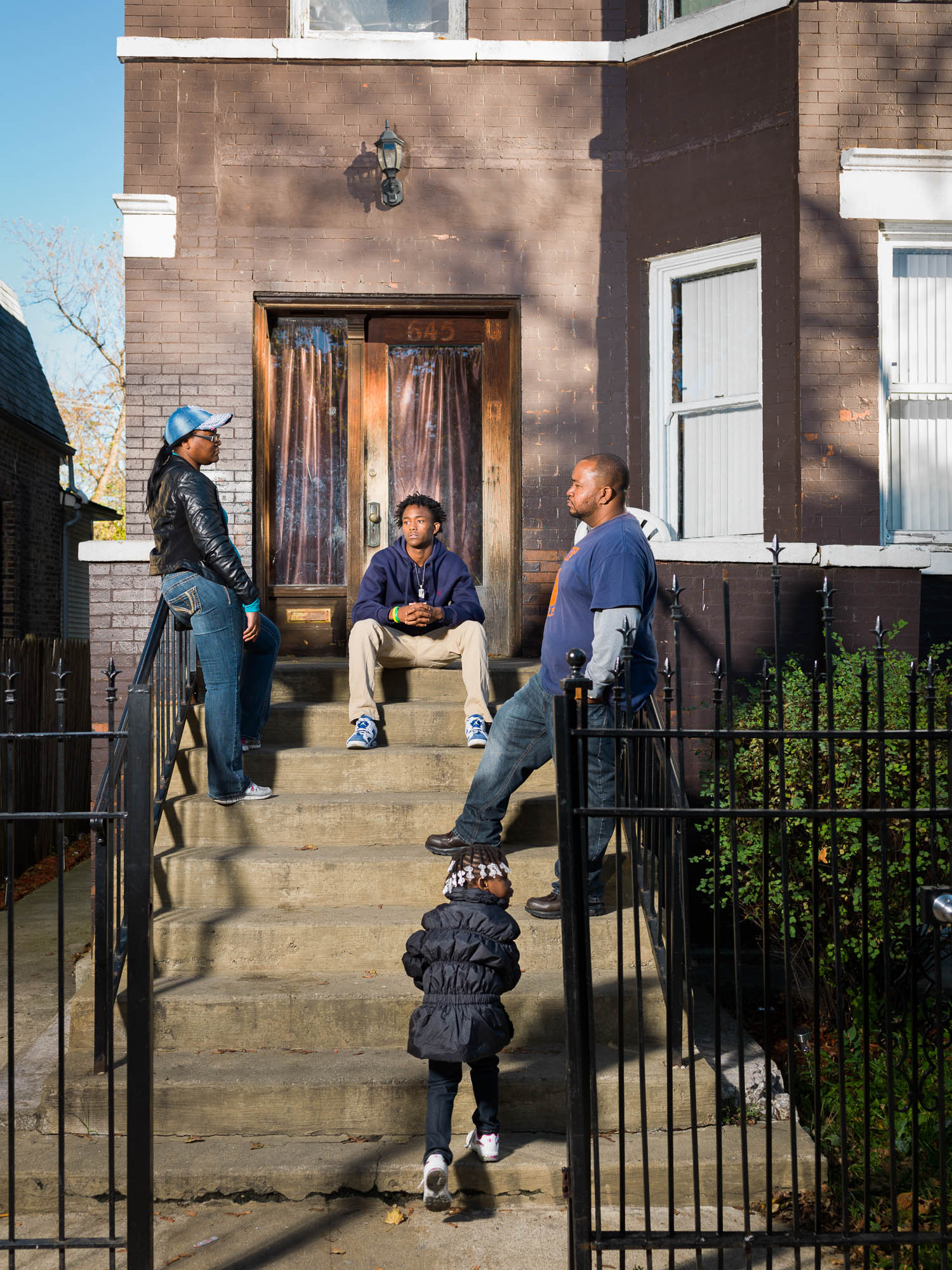 Cure Violence program coordinator Joshua Brooks speaks with Orr Academy high school student Jeryon Stevens (center,) his sister Jaziyah Vaughn and their mother Chrishona Hodges outside their Garfield Park home.