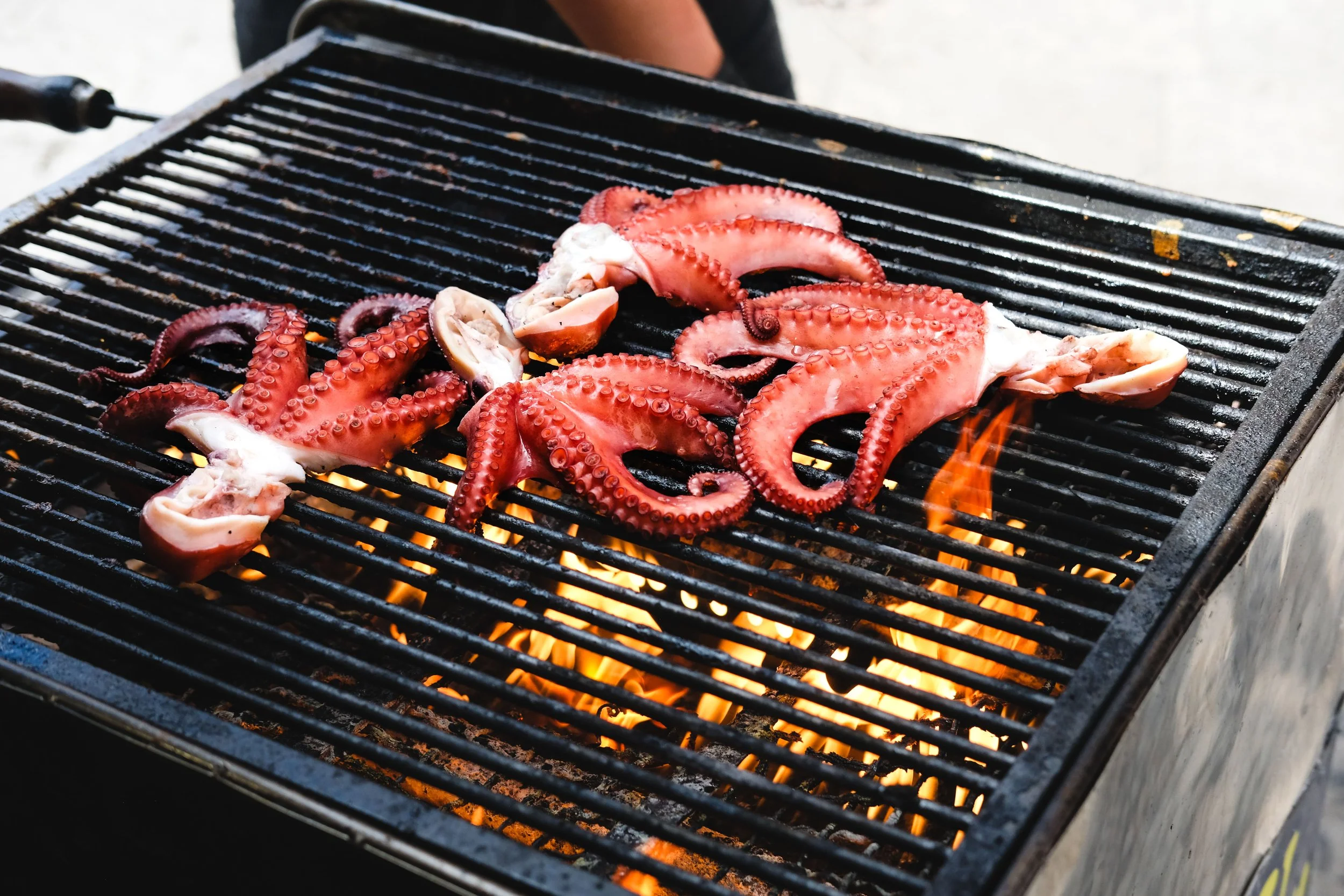  Editorial photo of octopus on an open fire grill in Palermo, Sicily. By travel food tourism photographer Amy Carson based in San Diego. 
