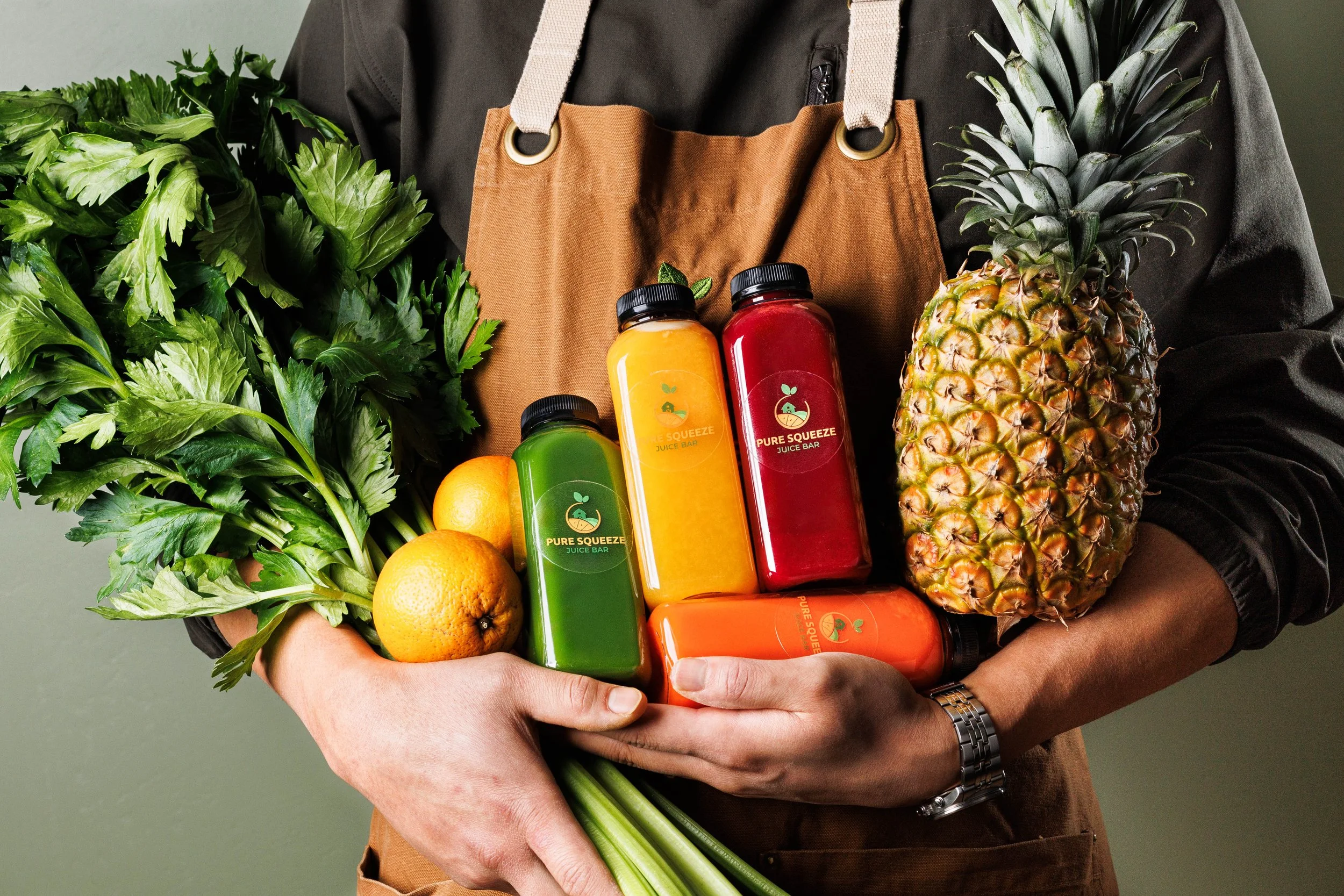 Commercial lifestyle product photo of a man holding bottles of juice and fresh produce. Photo by commercial food, drink and lifestyle product photographer Amy Carson.