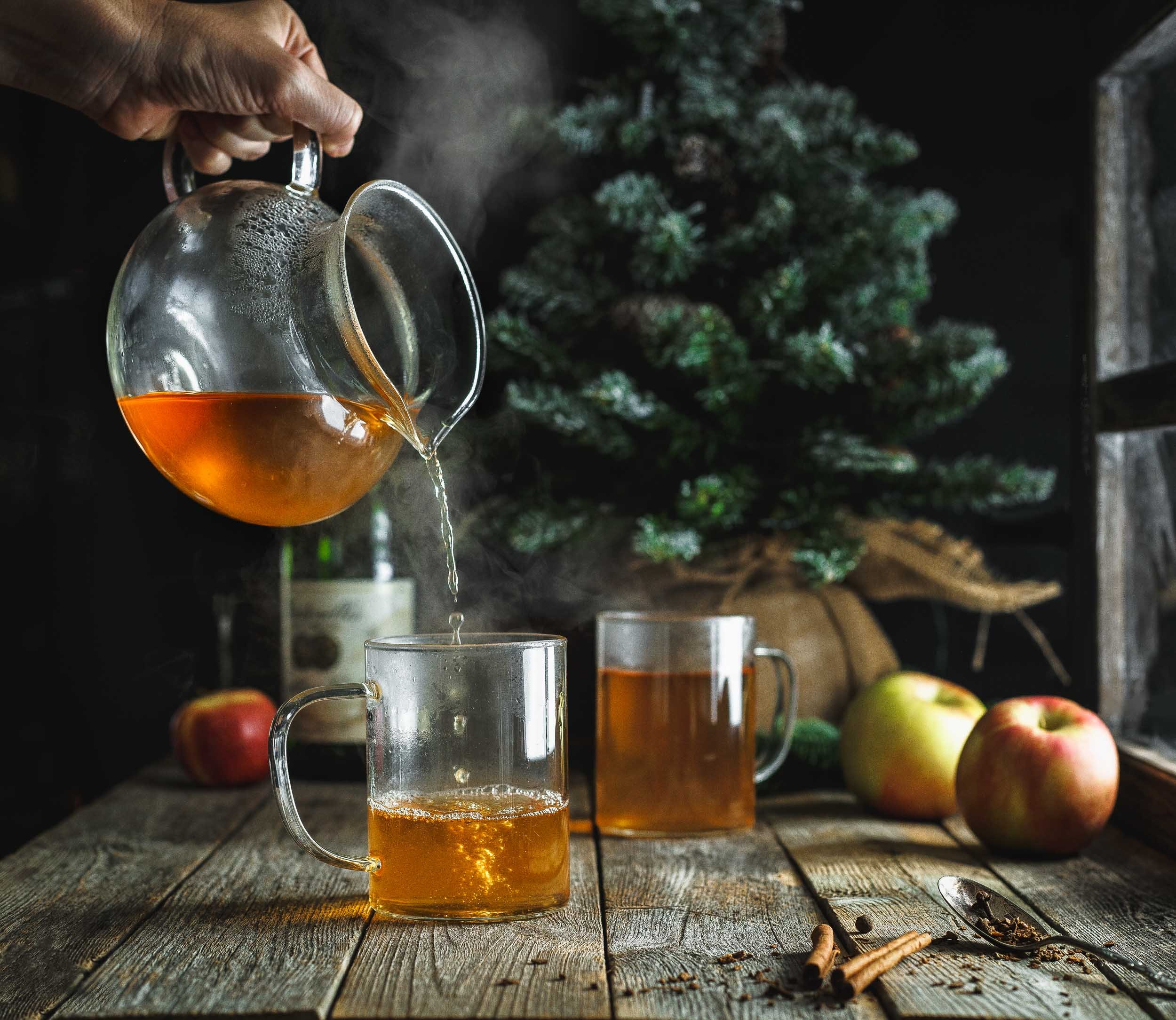 Pouring hot apple cider in a moody, rustic cabin scene. Commercial beverage photography for an advertising campaign.