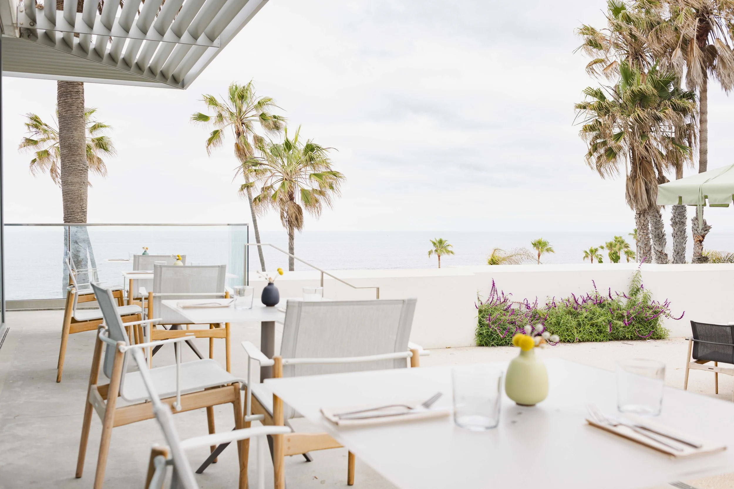  Commercial photo of the patio of a fine dining restaurant with palm trees and an ocean view. Shot by San Diego food and lifestyle photographer Amy Carson. 