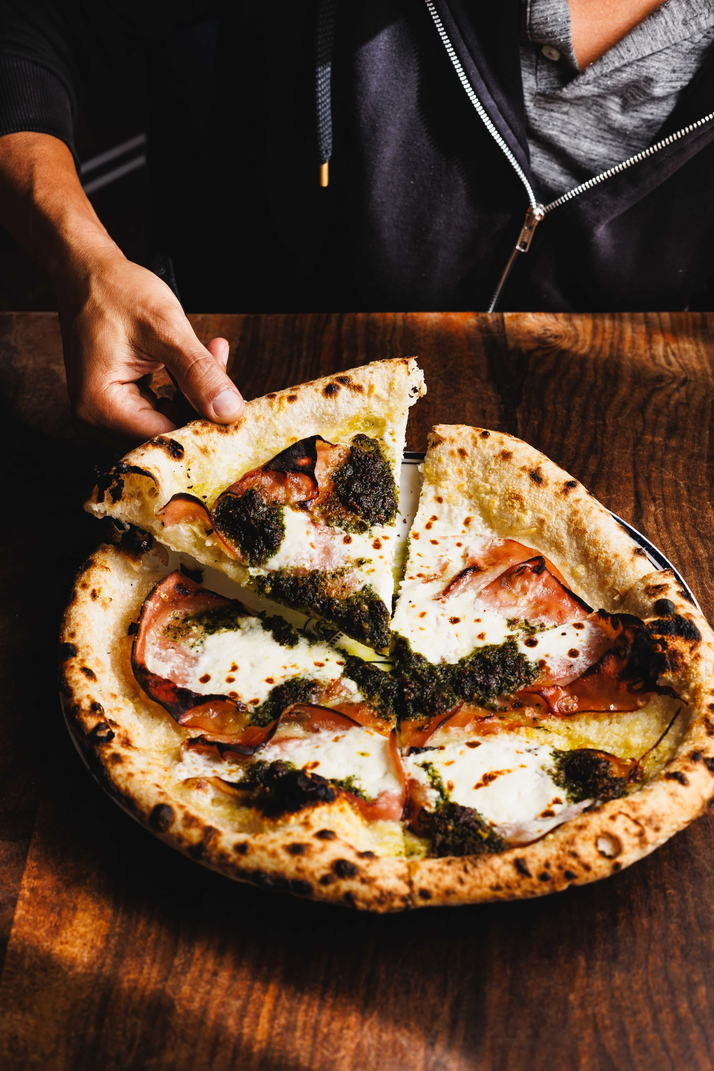  Commercial advertising photo of a man holding a slice of pizza at a restaurant. Photo shot by San Diego based food photographer Amy Carson. 