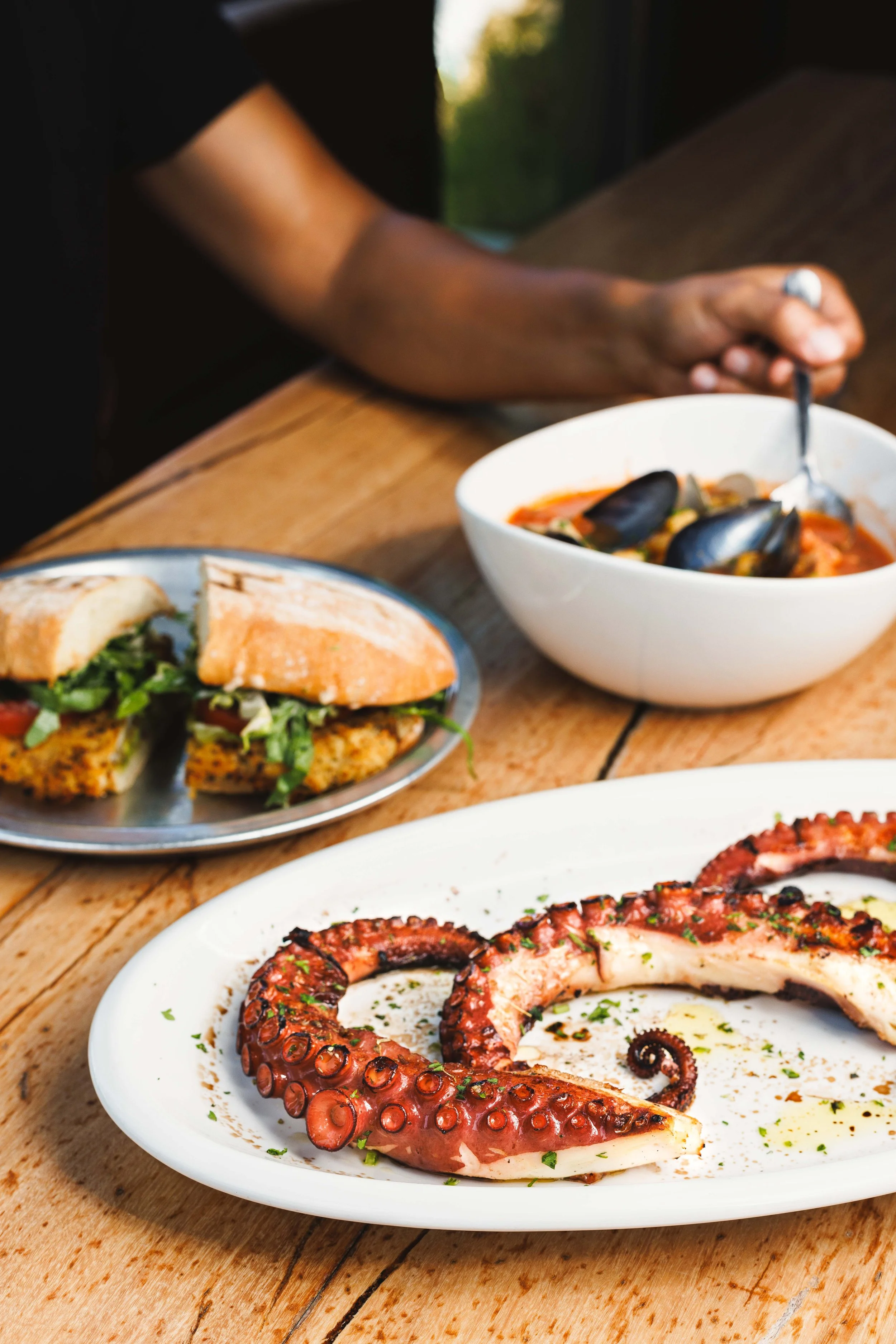  Commercial lifestyle photo of a seafood lunch outdoors on a rustic patio table with friends eating together. Shot by San Diego based food, lifestyle and travel photographer Amy Carson. 
