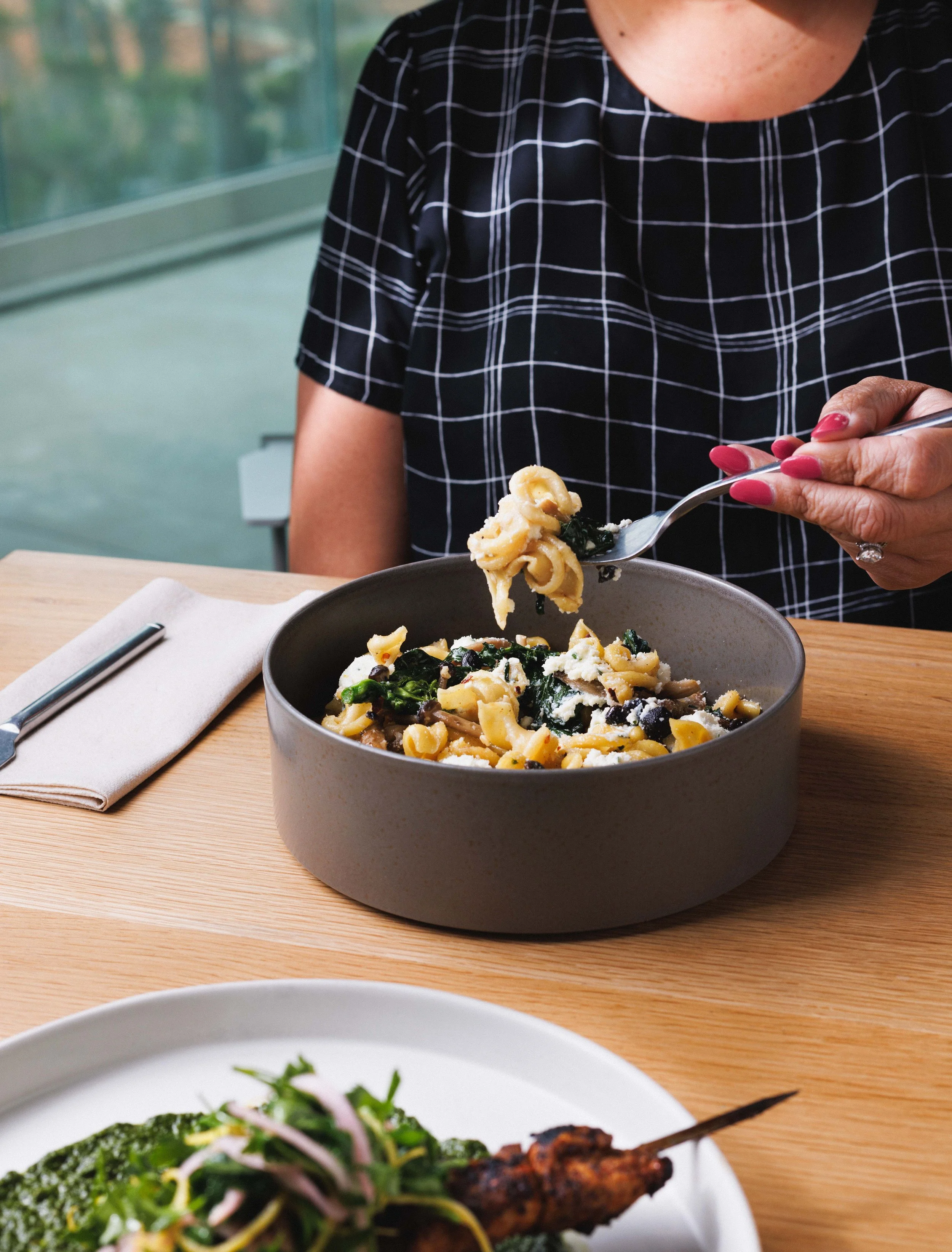  Commercial food lifestyle image of a woman eating pasta in a chic restaurant. Shot by San Diego food photographer Amy Carson. 