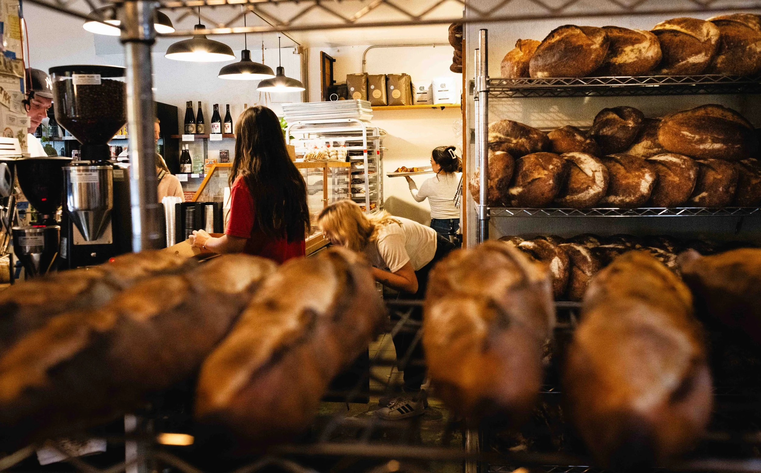  Editorial photo of a busy bakery behind the scenes with lots of bread loaves around. Photo by commercial food and lifestyle photographer Amy Carson, in San Diego, California. 