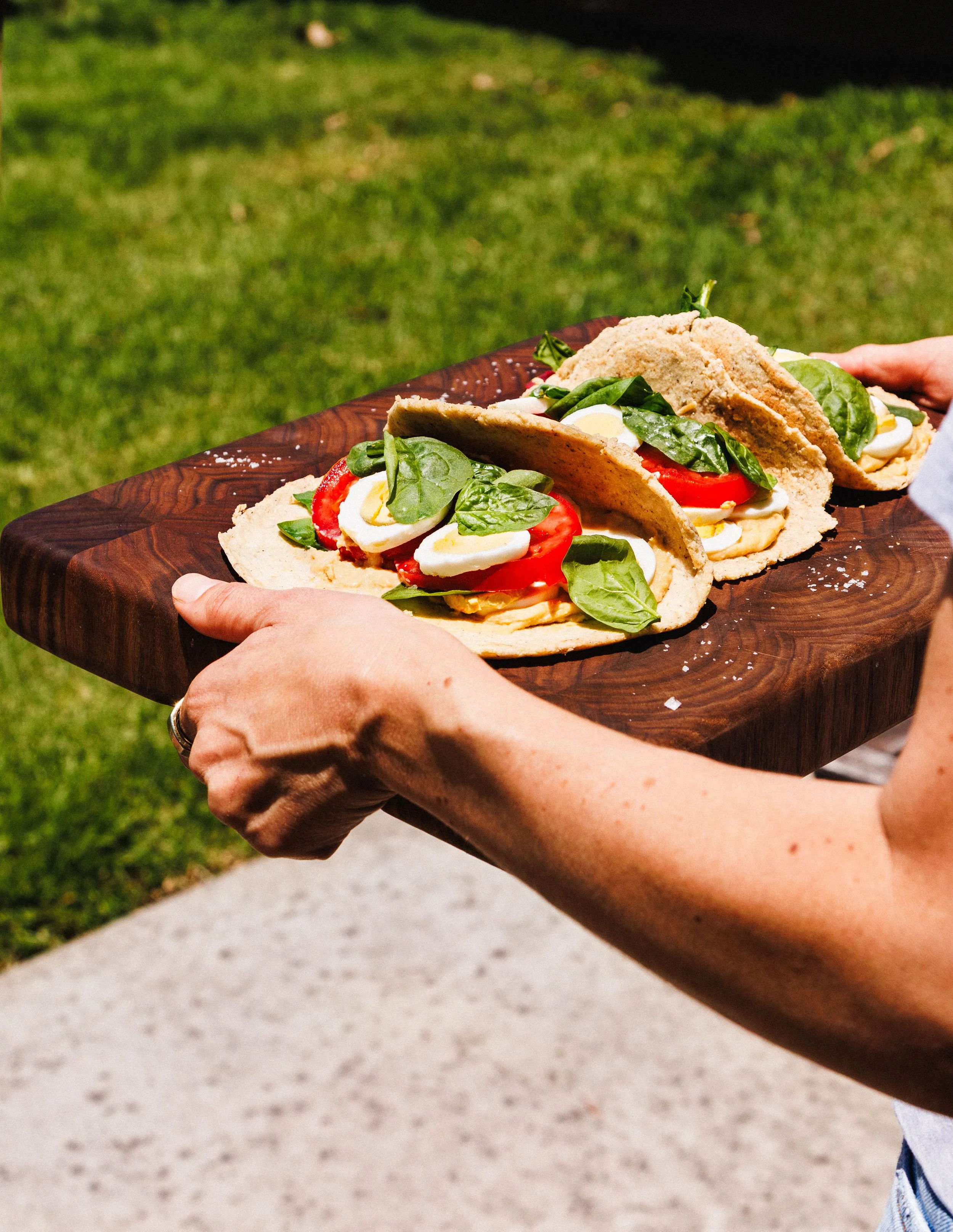  Commercial food photo of woman carrying a tray of pitas outdoors. Shot by San Diego food and lifestyle photographer Amy Carson. 