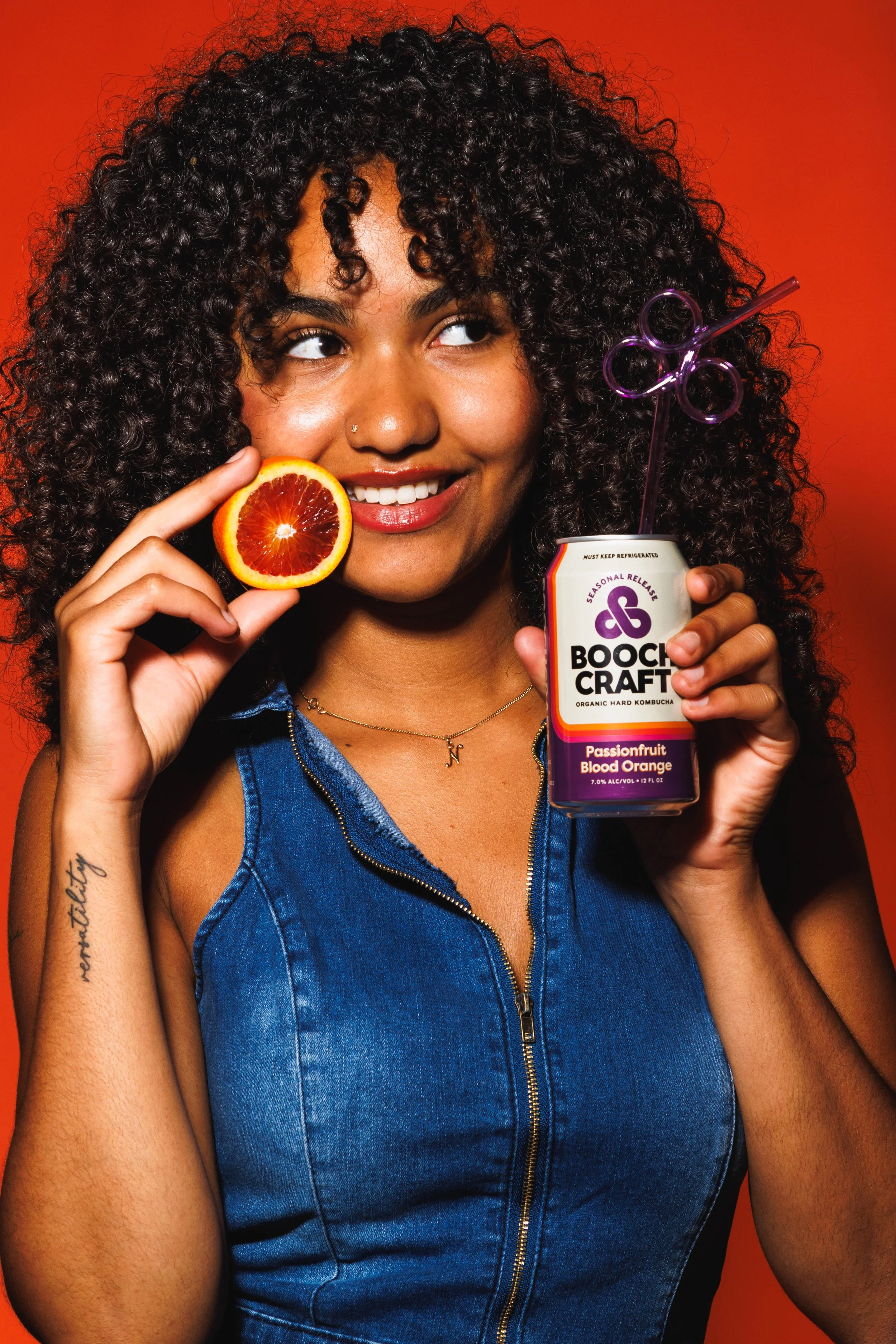 Commercial product photo of a young woman holding a canned kombucha and fruit. By San Diego product photographer Amy Carson.