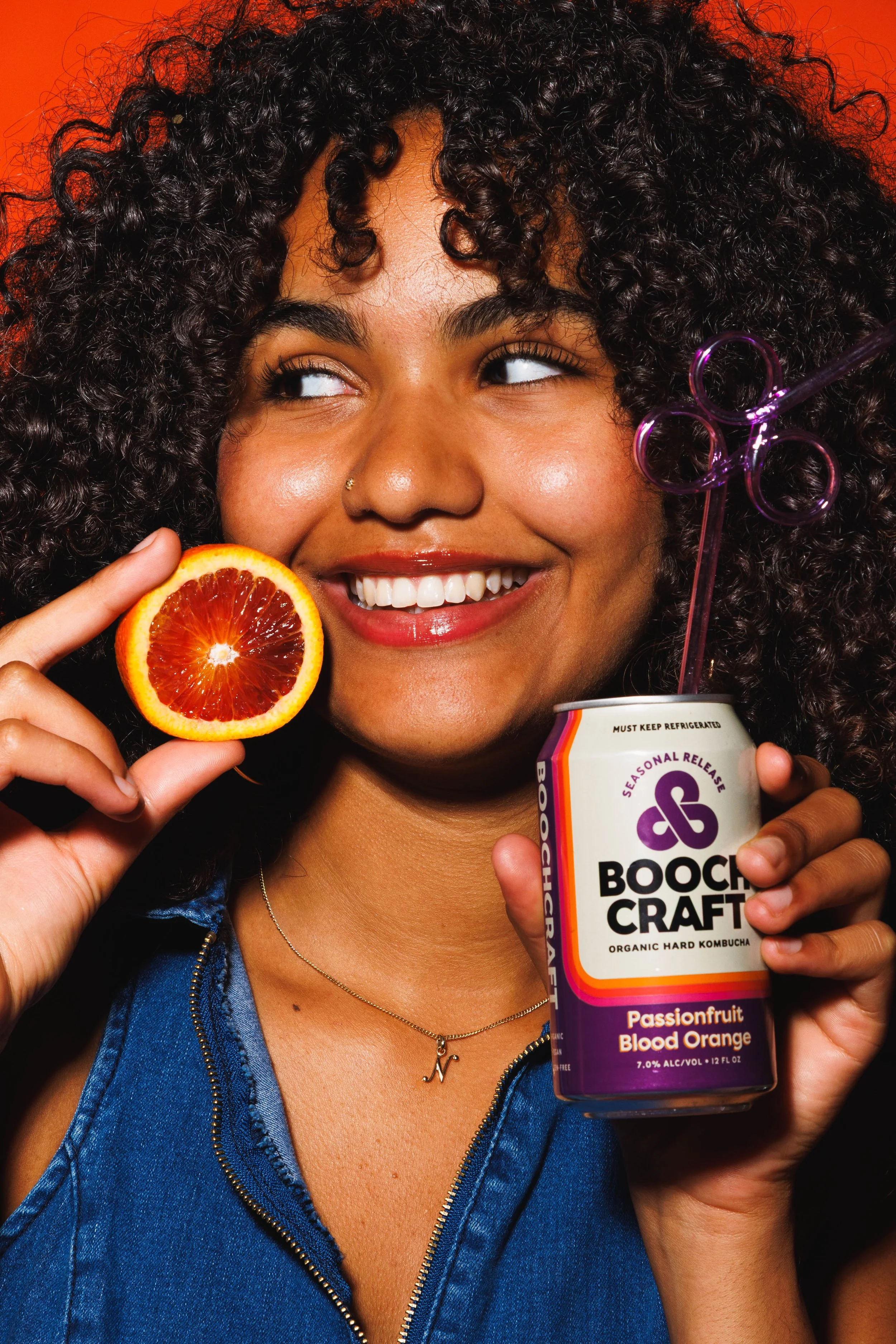 Commercial product photo of a young woman holding a canned beverage and blood orange. Shot by San Diego product photographer Amy Carson.