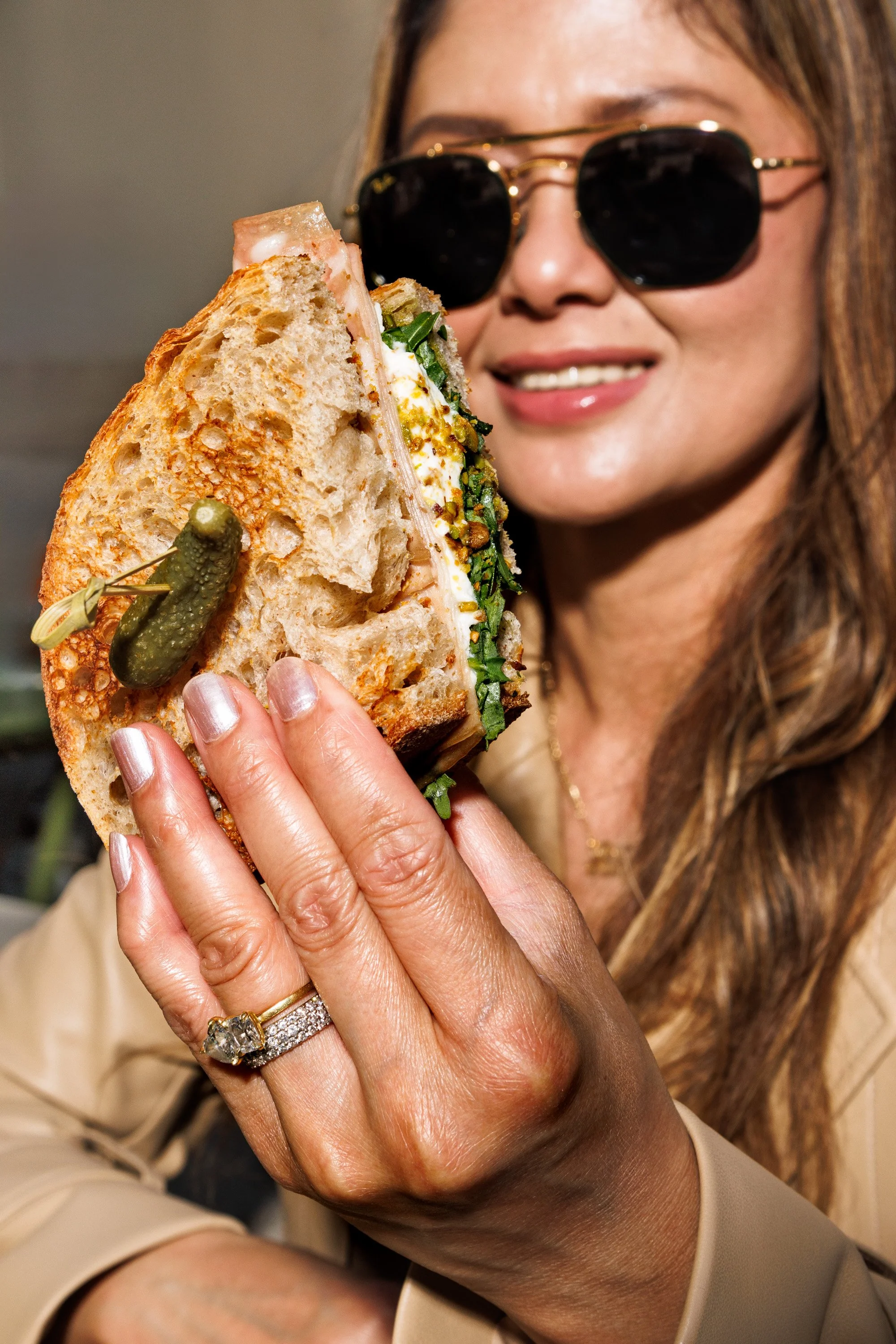 Commercial lifestyle photo of a woman holding a sandwich.