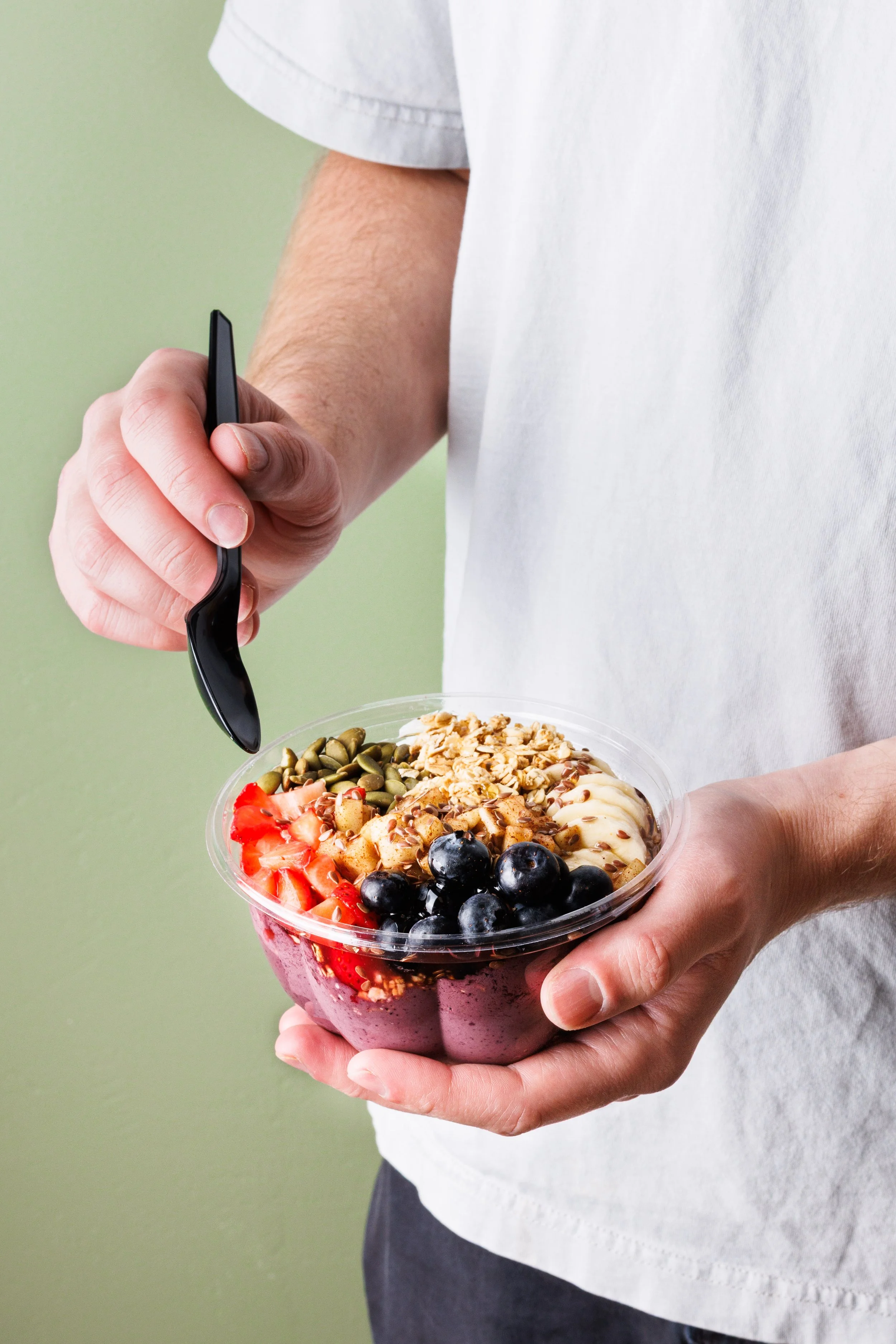 Commercial lifestyle product photo of a young man eating an acai bowl. Shot by San Diego food and lifestyle product photographer Amy Carson.