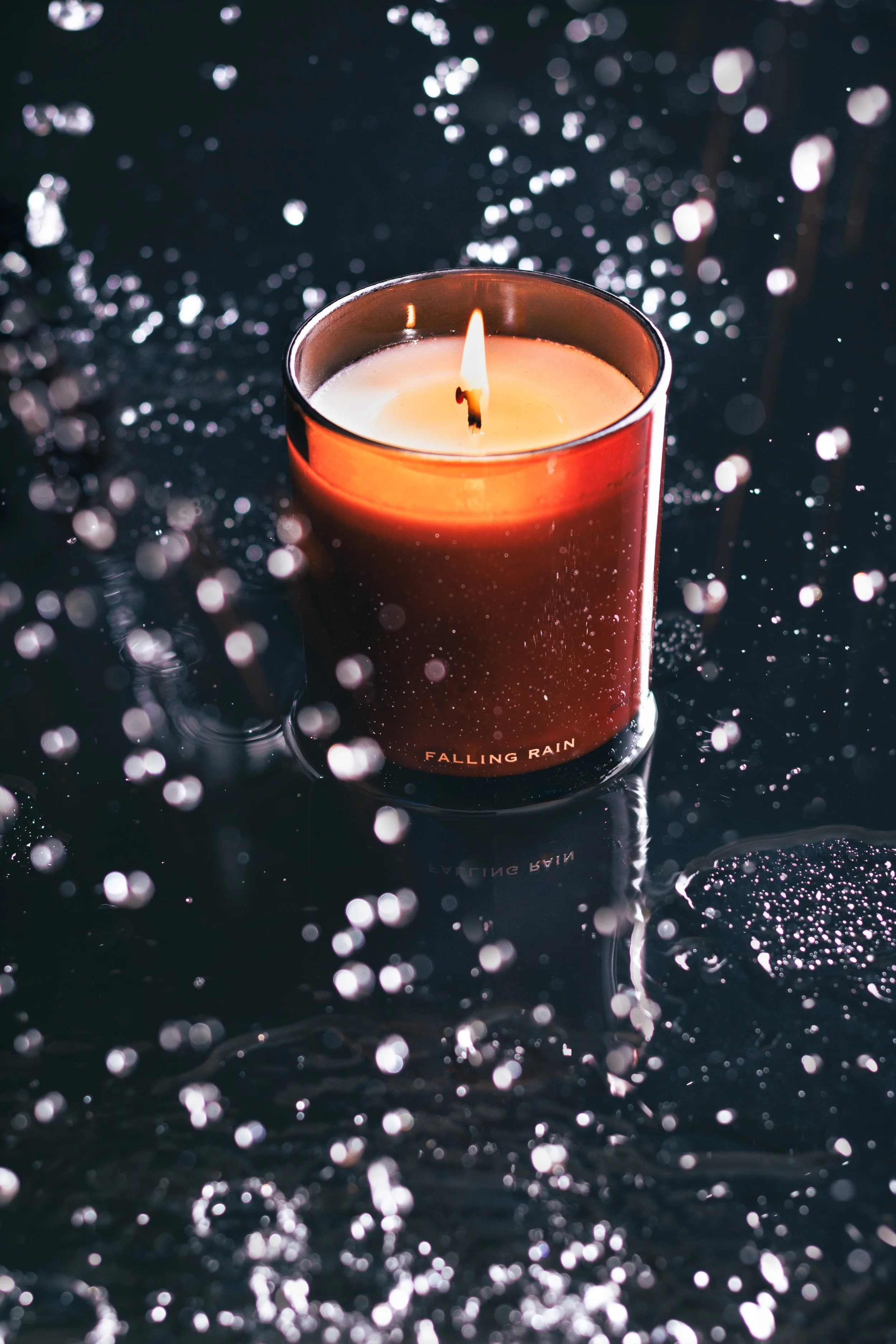Commercial lifestyle product photo of a luxury candle in the rain.