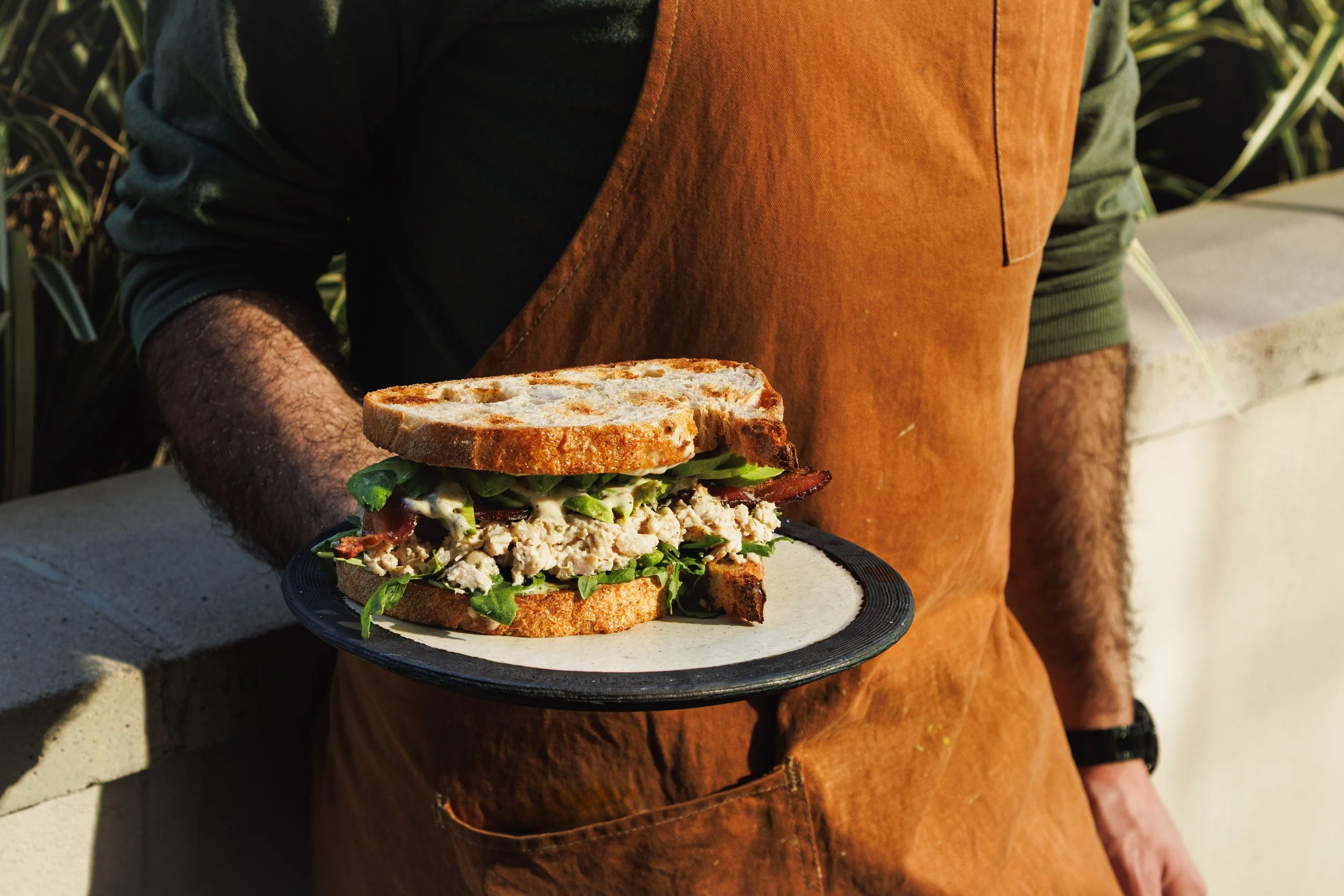 Commercial food lifestyle photo of a chef holding a chicken salad sandwich in San Diego.