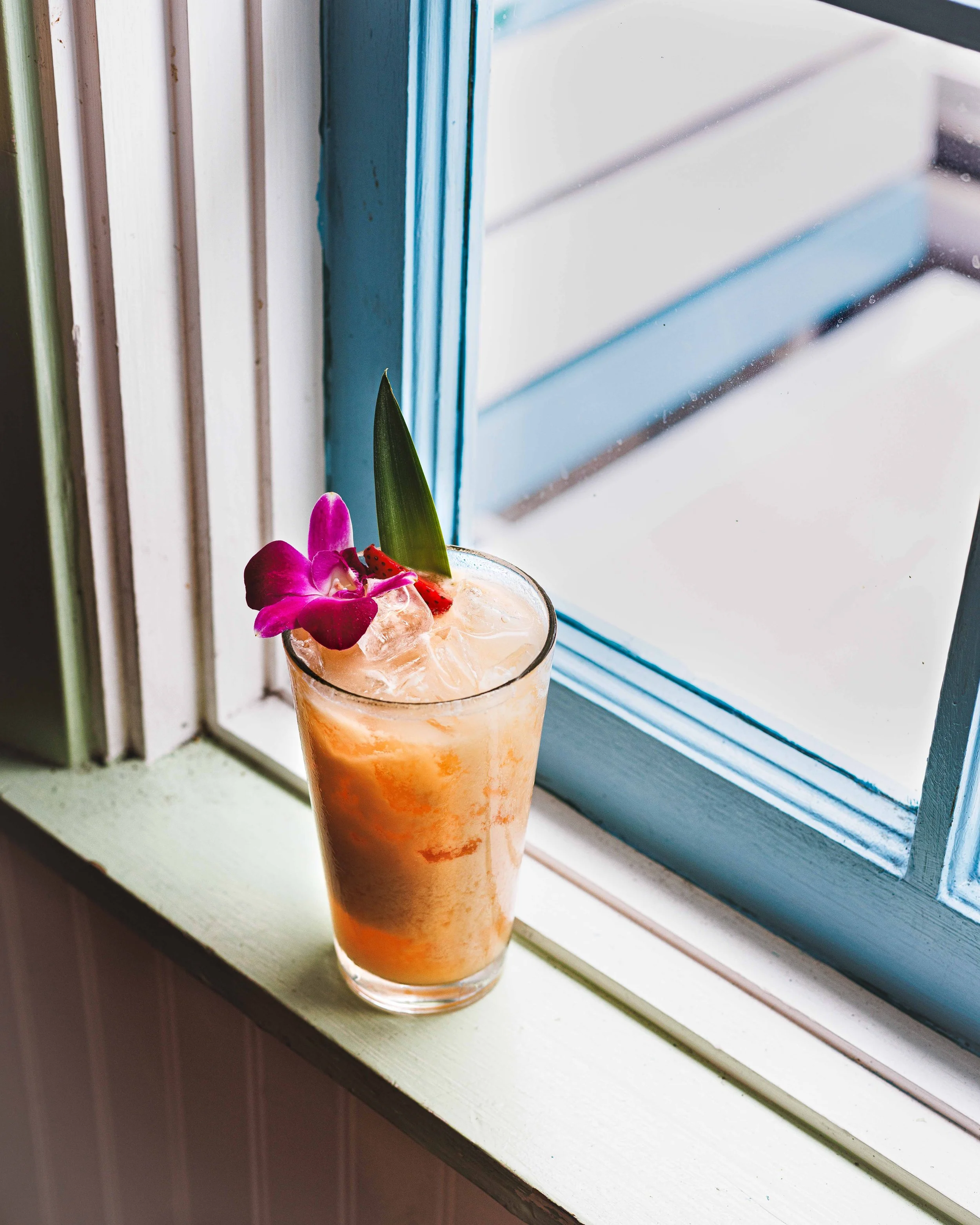 Editorial photo of a cocktail by a windowsill in a cafe. By Amy Carson, San Diego drinks photographer.