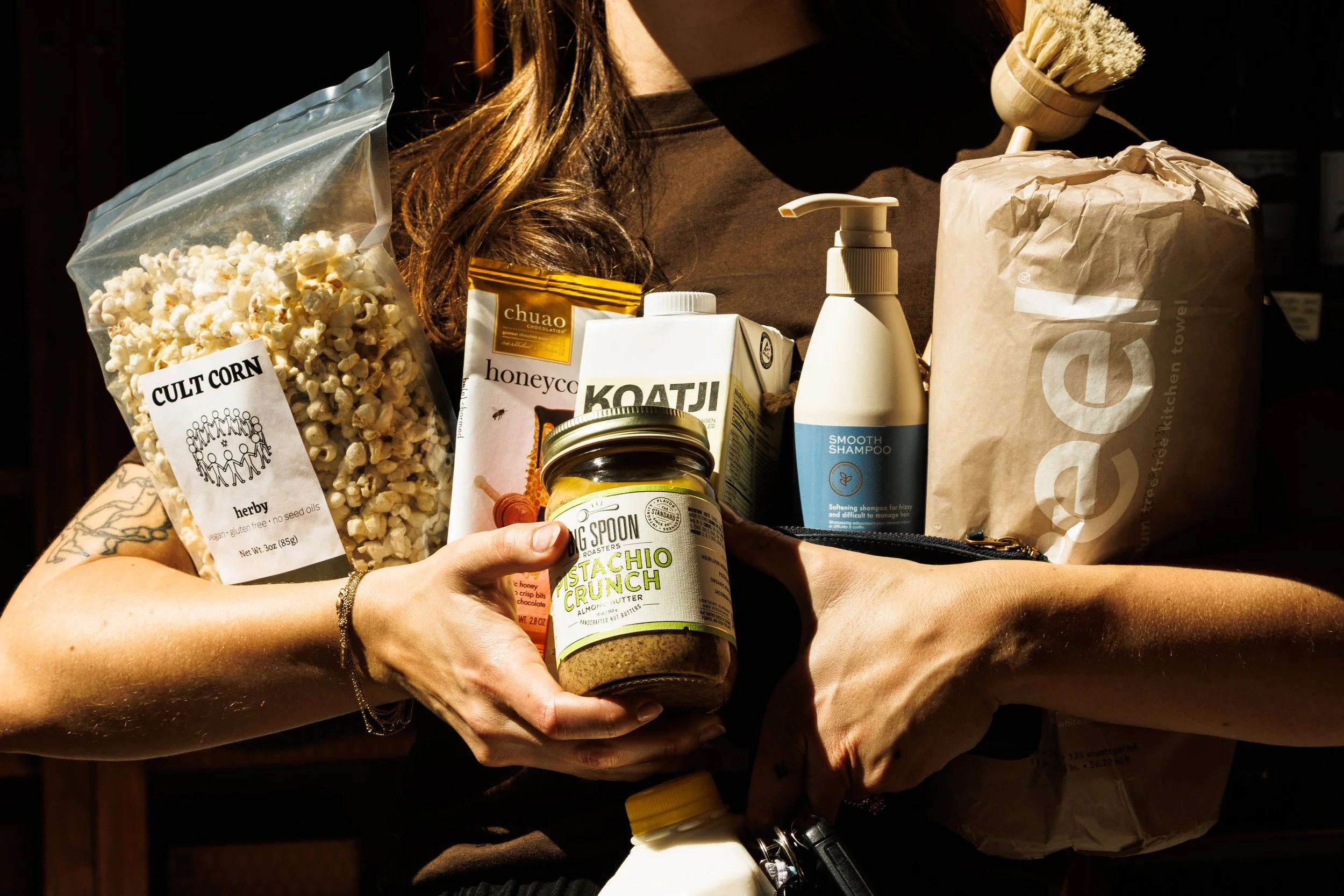 Commercial lifestyle product photo of woman holding products in sunlight.