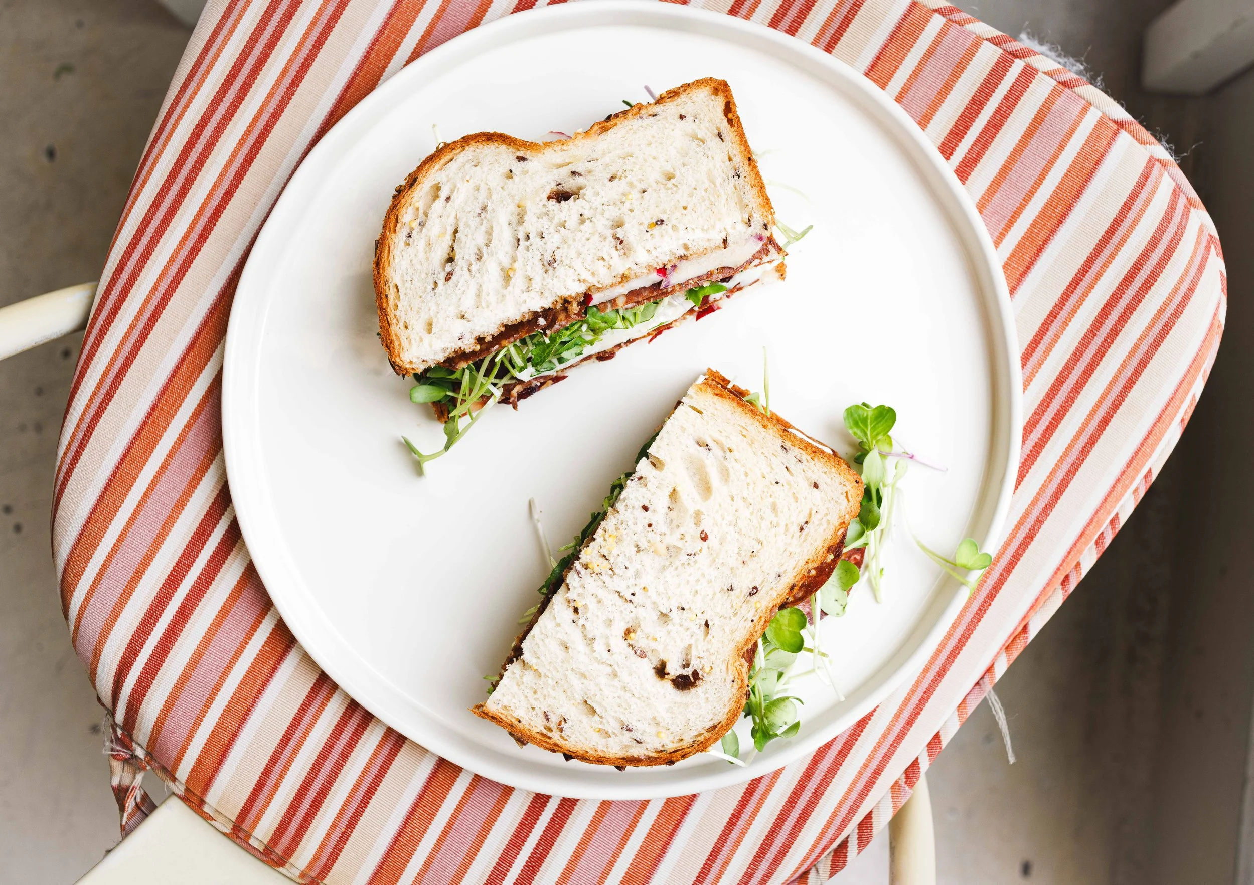 Editorial photo of a sandwich on a candycane striped chair in a cafe in San Diego. By commercial food photographer Amy Carson.