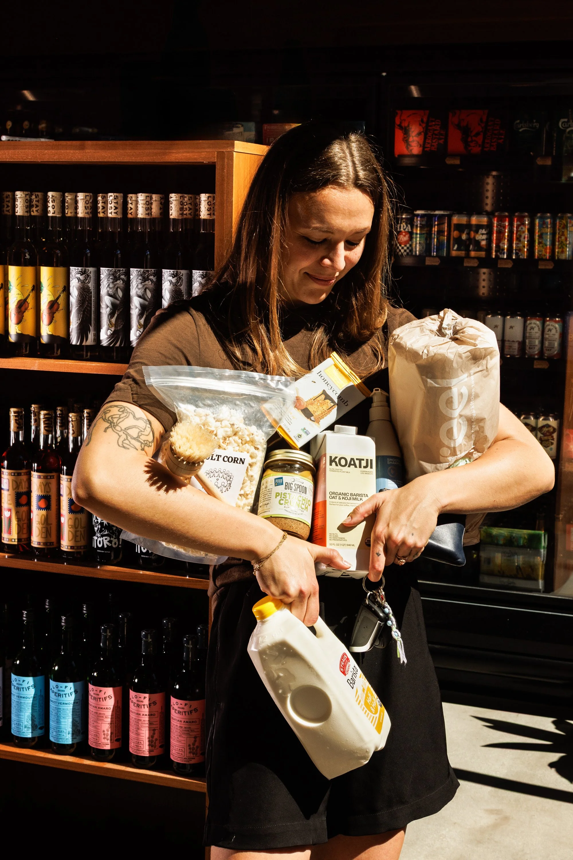 Commercial photo of a woman holding products with beverage bottles behind her. By Amy Carson.