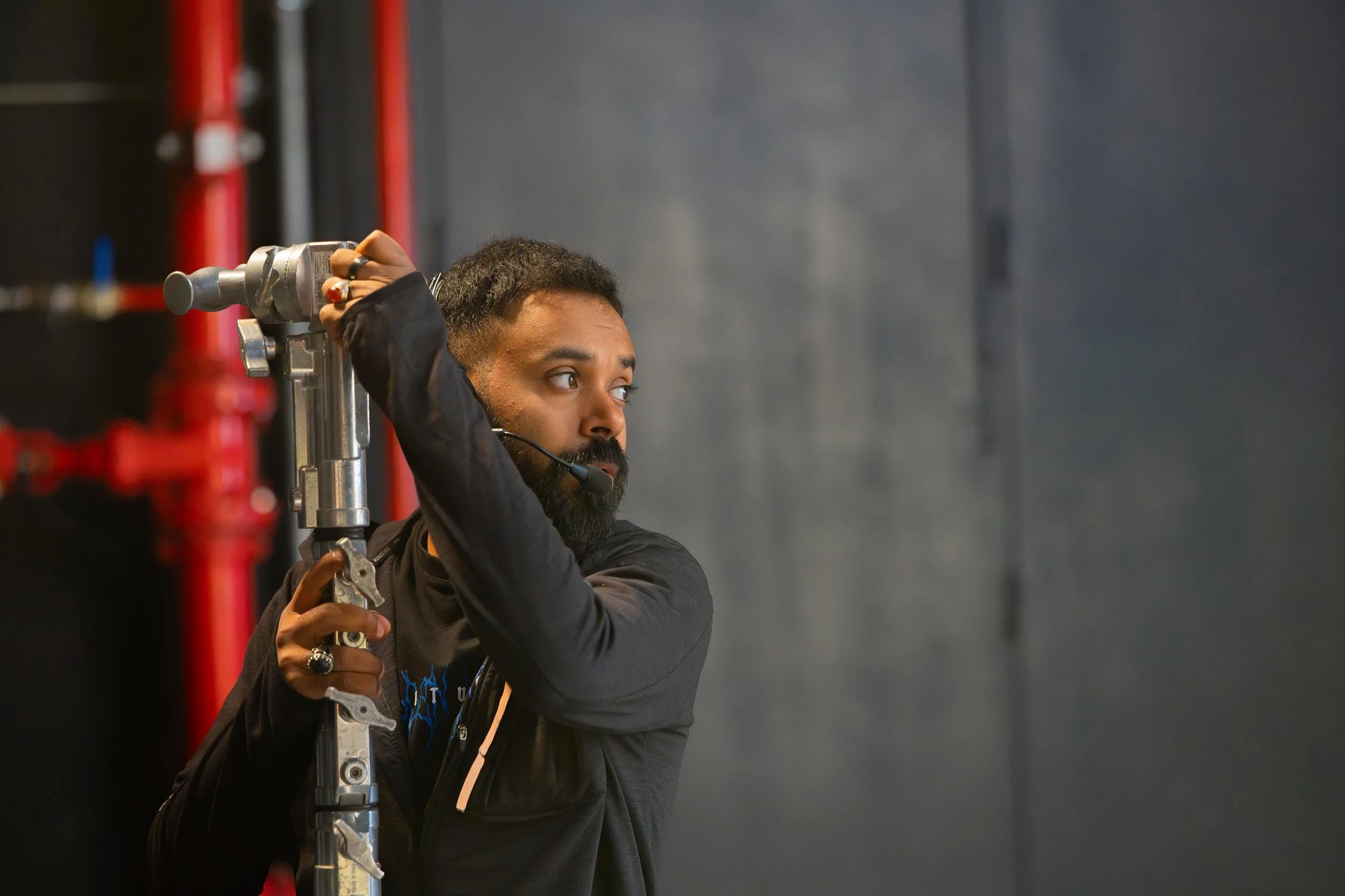 Ahlan Simsim unit still: A crew member wearing a headset adjusts a silver equipment stand in a studio.
