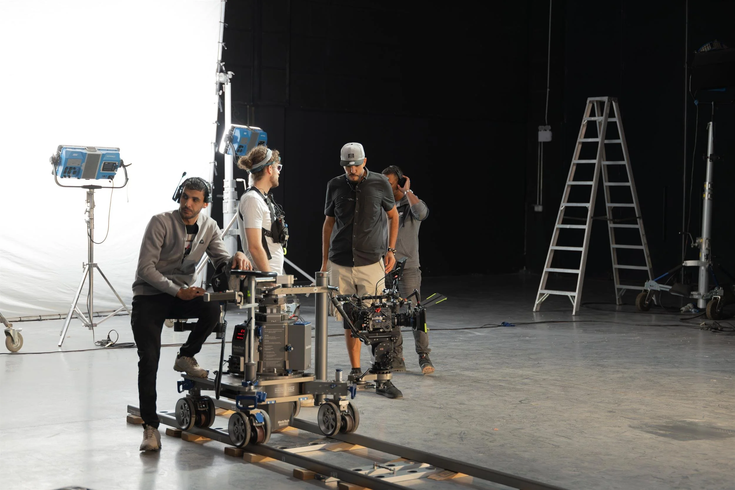 Ahlan Simsim unit still: crew work with a camera on a dolly and tracks in a studio.