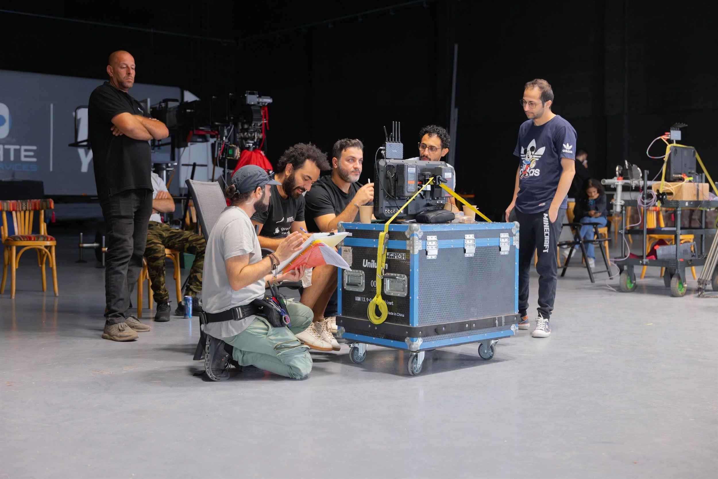 Ahlan Simsim unit still: crew huddle around a rolling equipment case and production monitor.