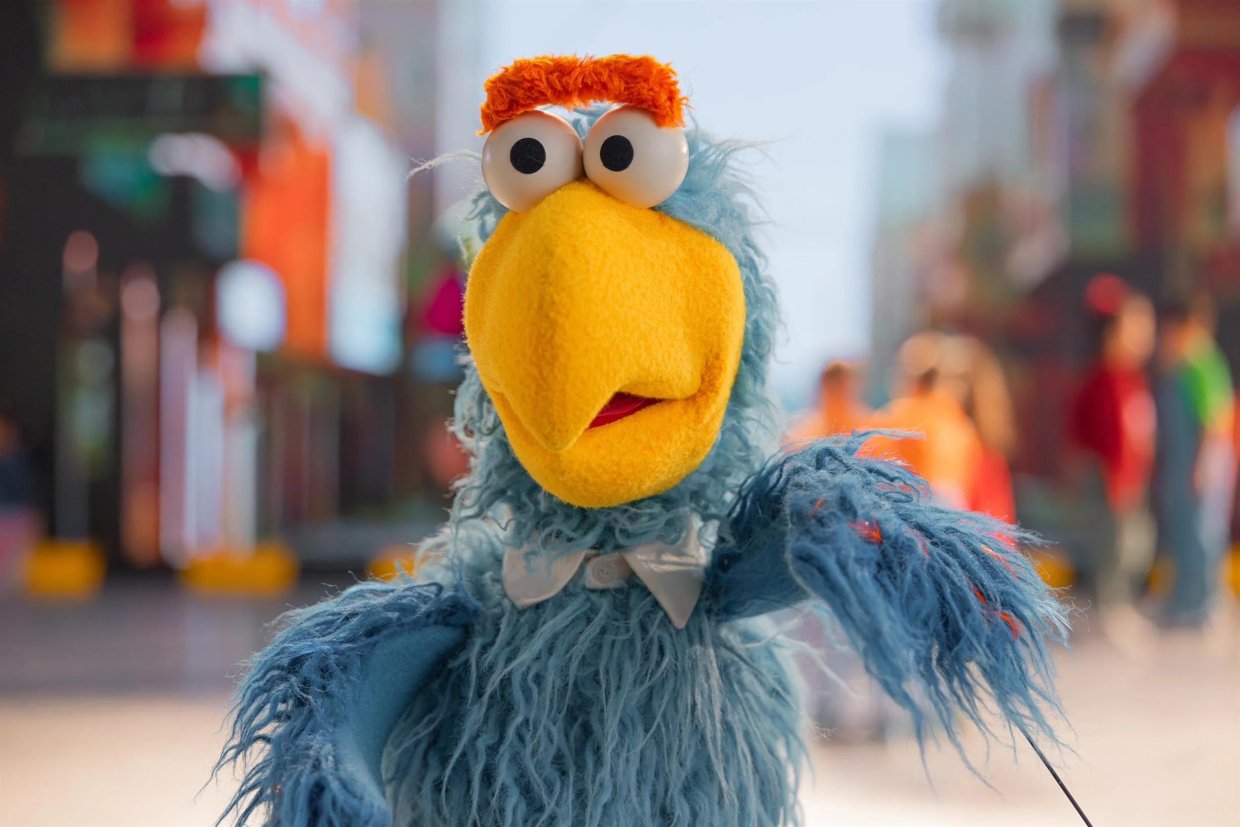 Ahlan Simsim unit still: close-up of a blue Muppet with an orange unibrow, yellow beak, and white bowtie.
