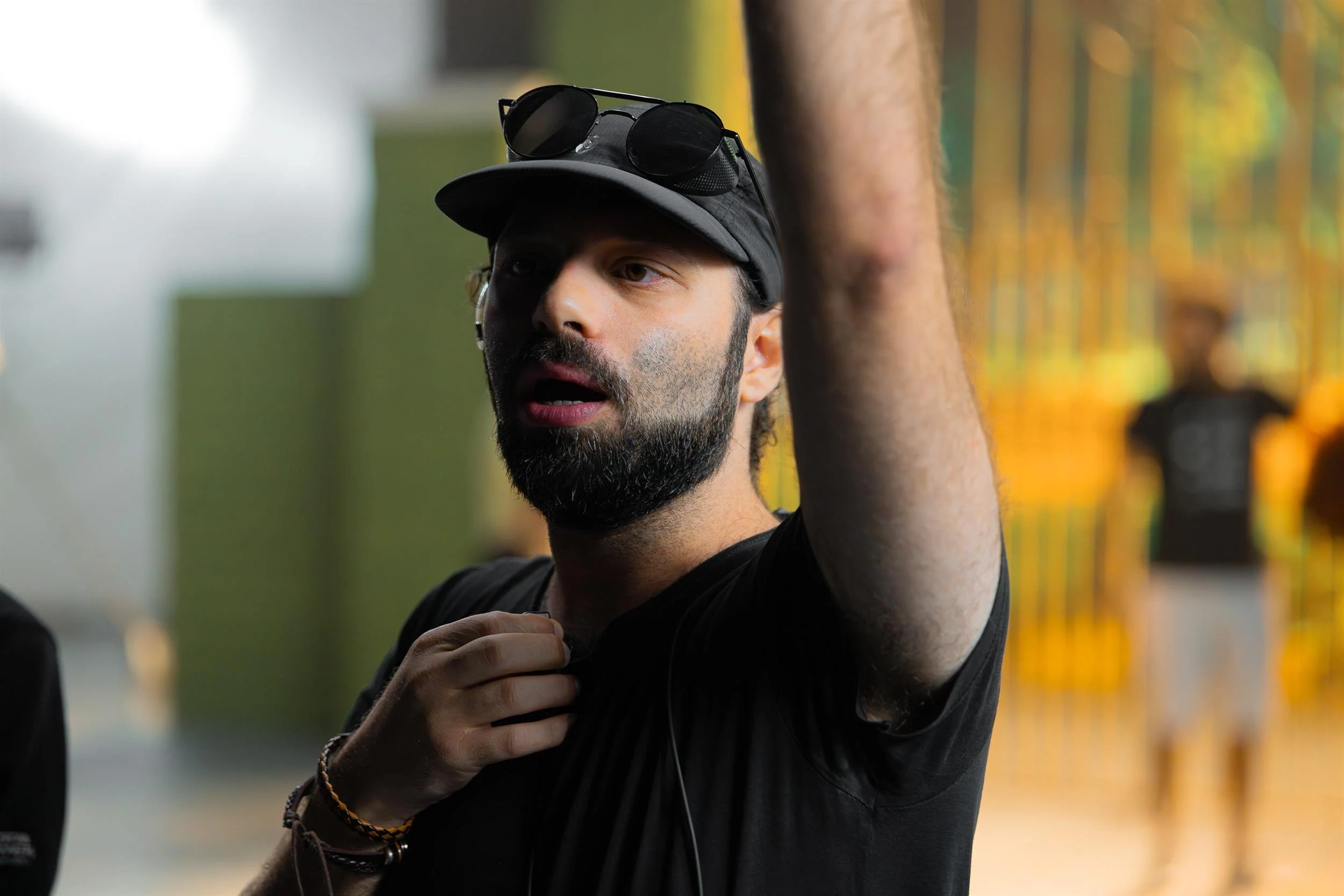 Ahlan Simsim unit still: A bearded crew member in a black cap and t-shirt speaks on set.