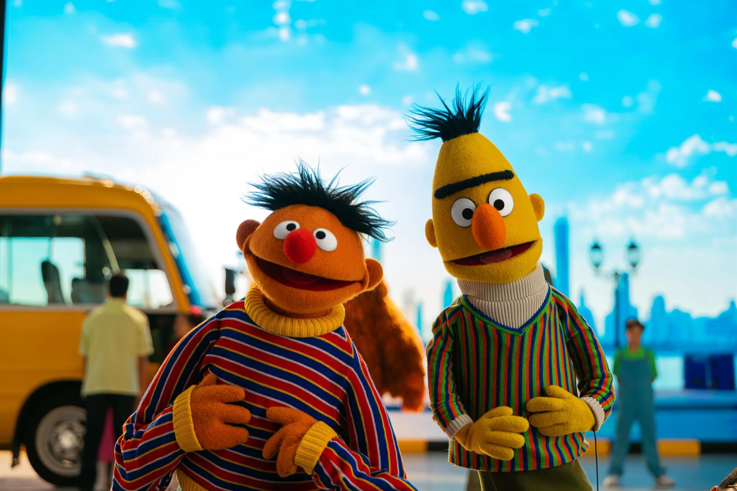 Ahlan Simsim key art: Ernie and Bert standing in front of a yellow school bus under a blue sky