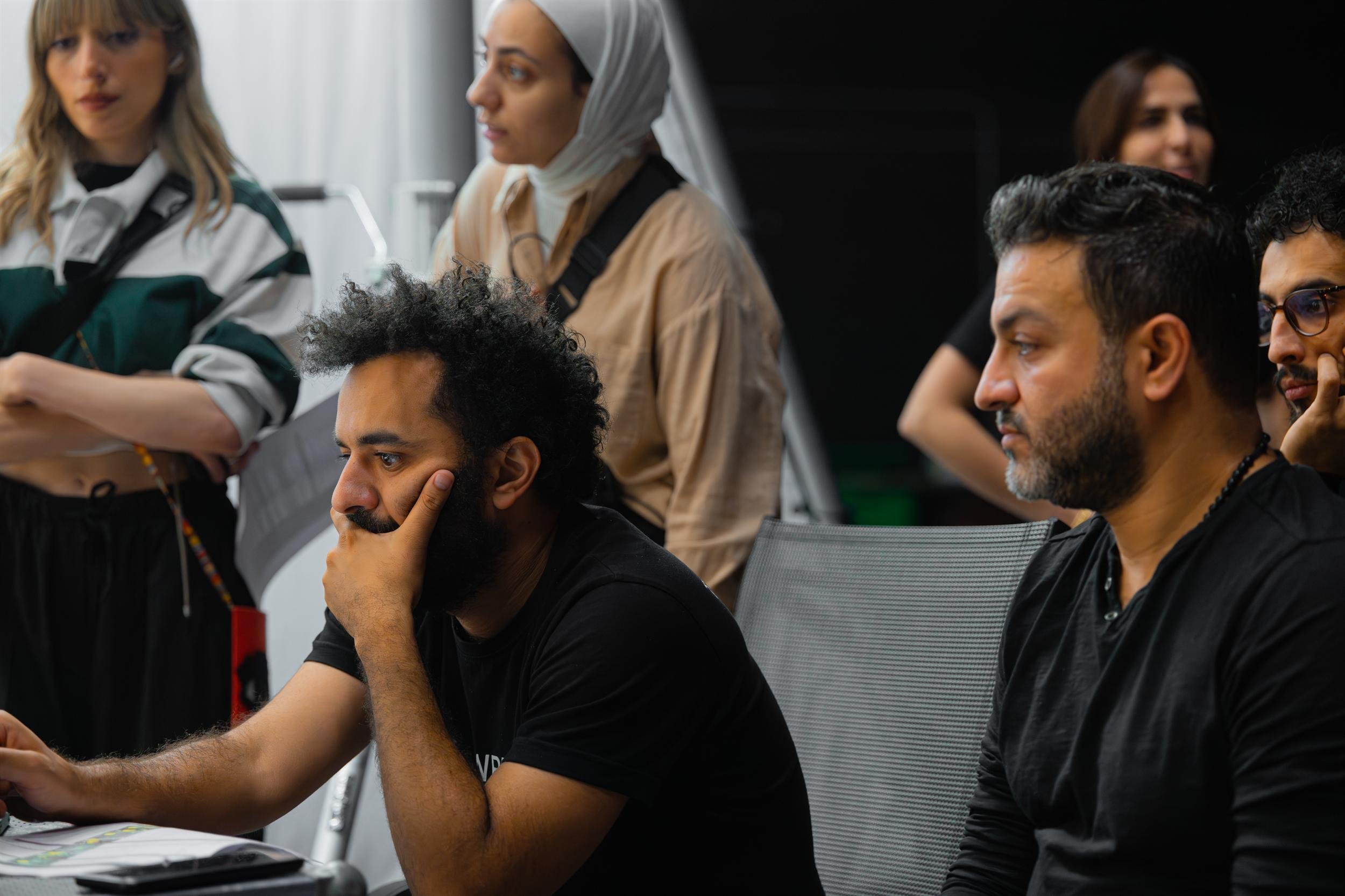 Ahlan Simsim unit still: A group of crew members intently watch production in a dark studio.