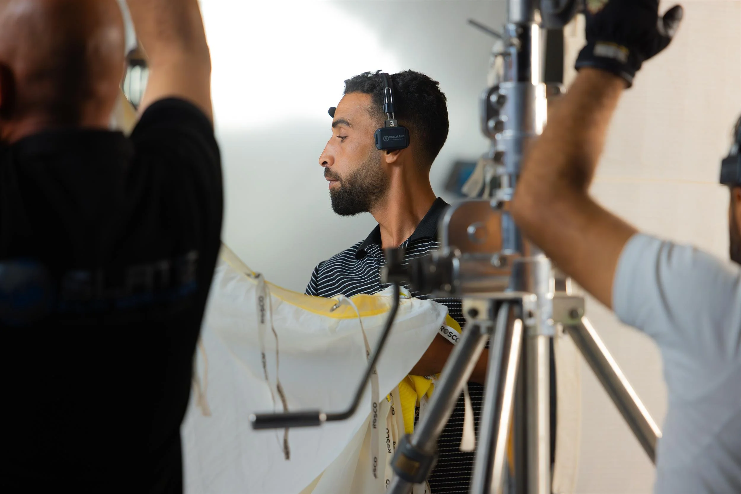 Ahlan Simsim unit still: A crew member wearing a headset holds a lighting silk on a studio set.