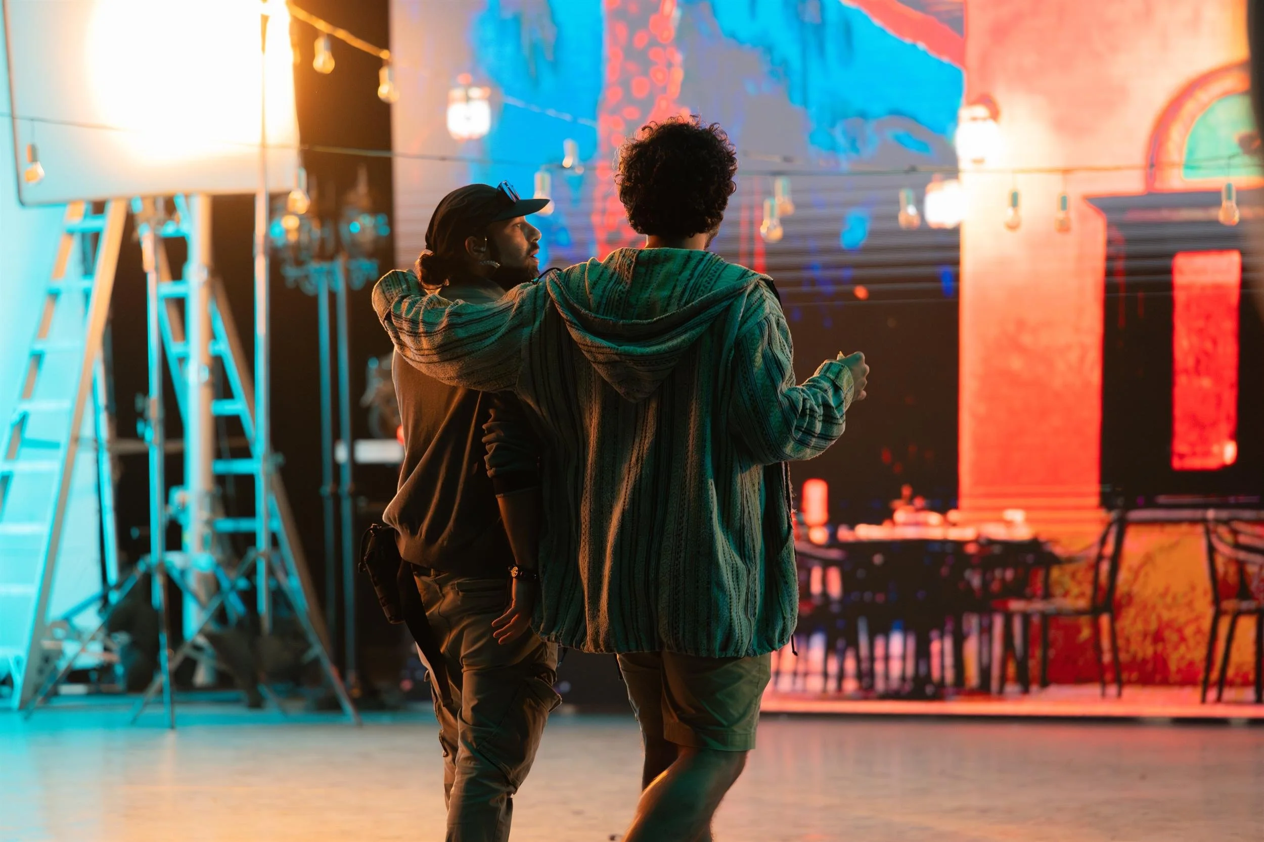 Ahlan Simsim unit still: two crew members stand with arms around each other looking at an LED street backdrop.