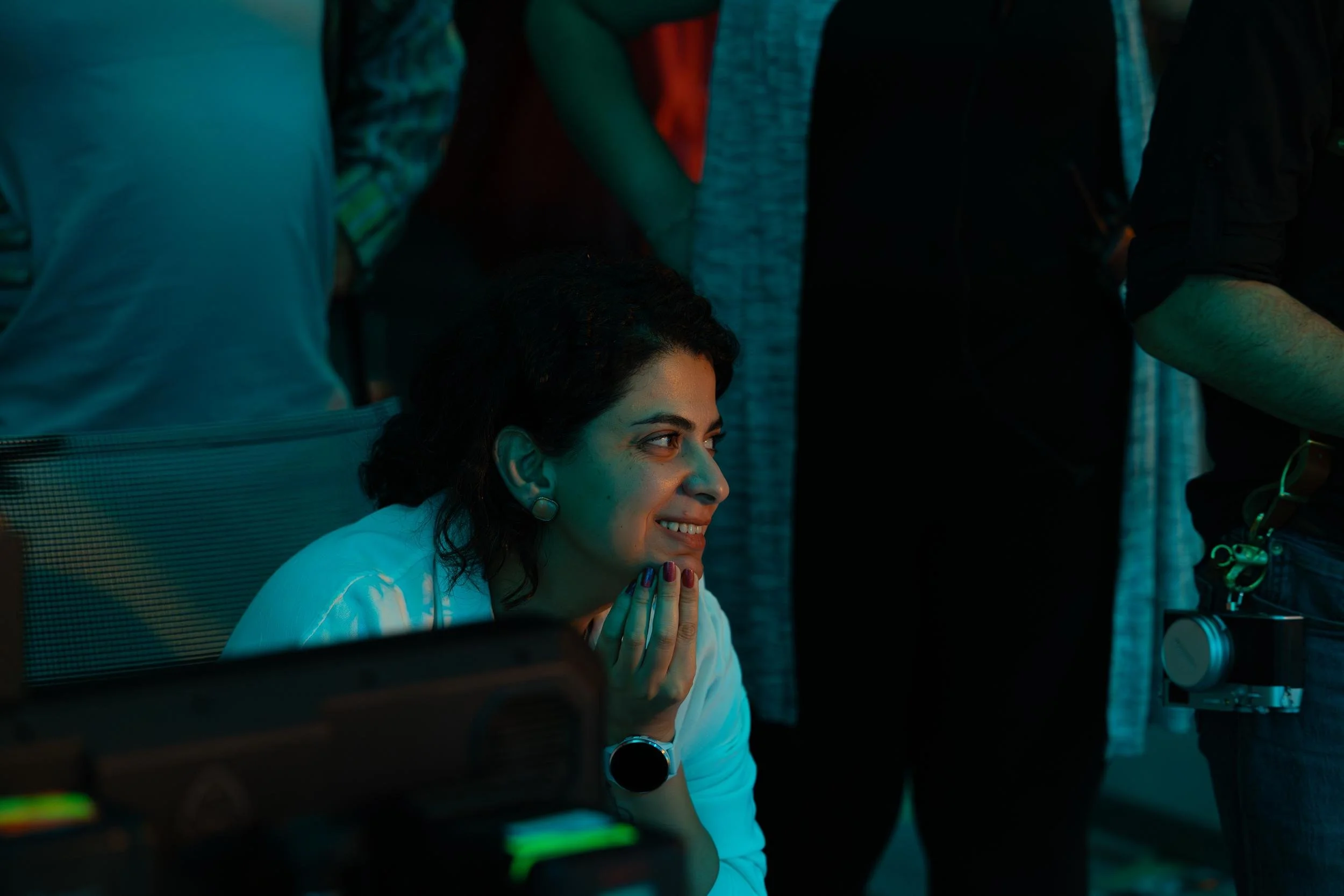 Ahlan Simsim unit still: a smiling crew member with her hand on her chin looks toward a monitor.