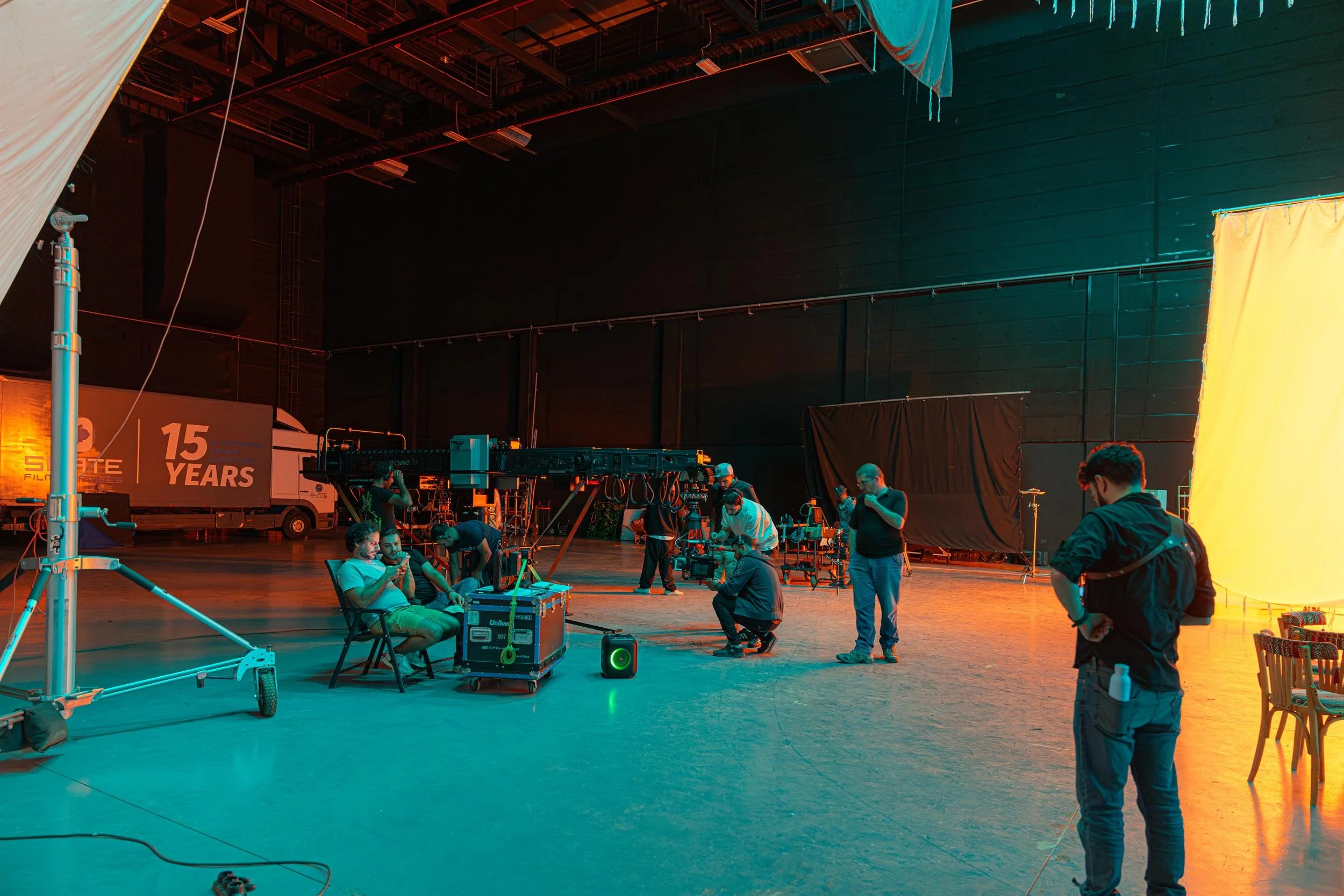 Ahlan Simsim unit still: crew work around a camera crane in a large soundstage with teal and orange lighting.