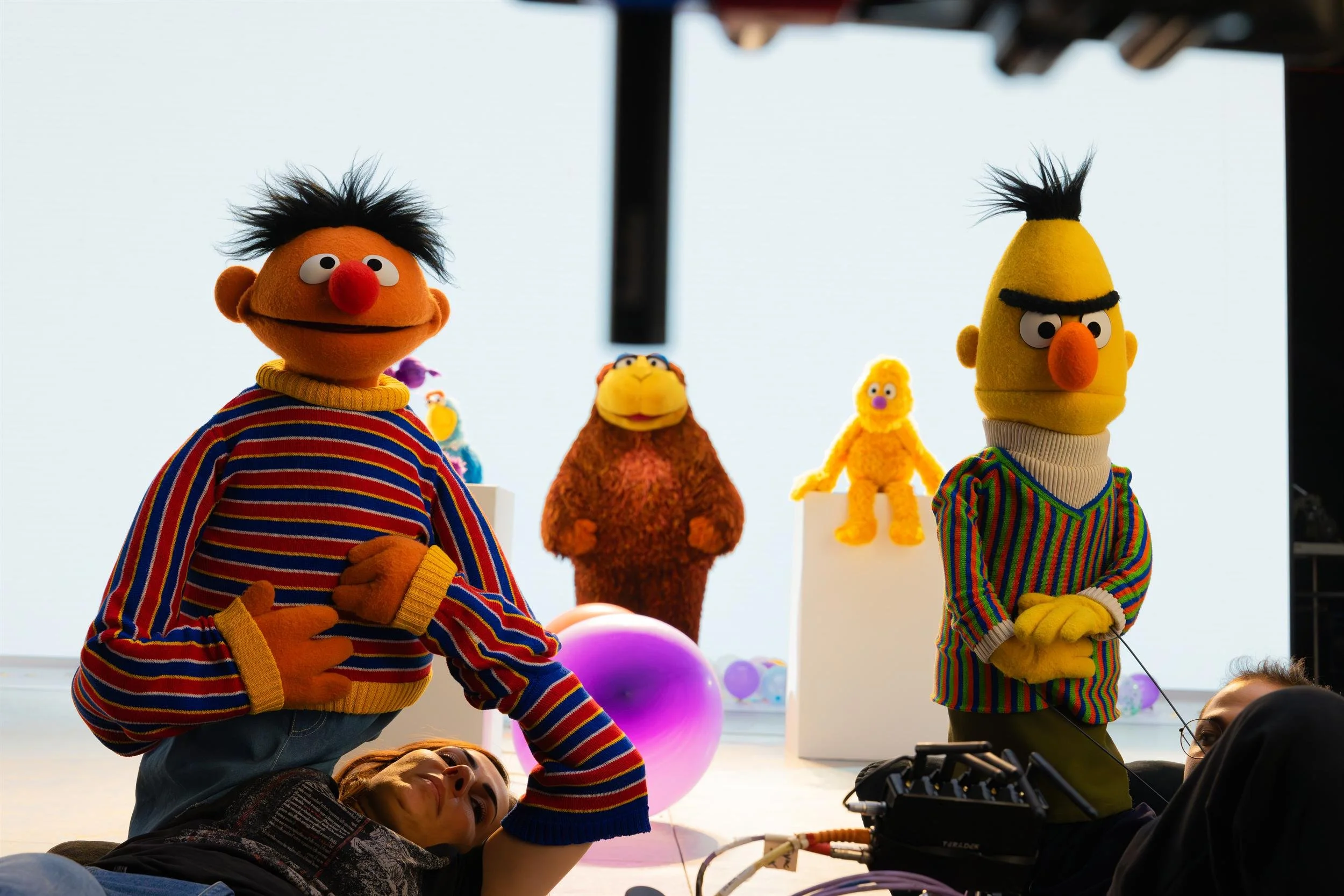Ahlan Simsim unit still: puppeteers lie on the floor operating Ernie and Bert in front of a white studio backdrop.