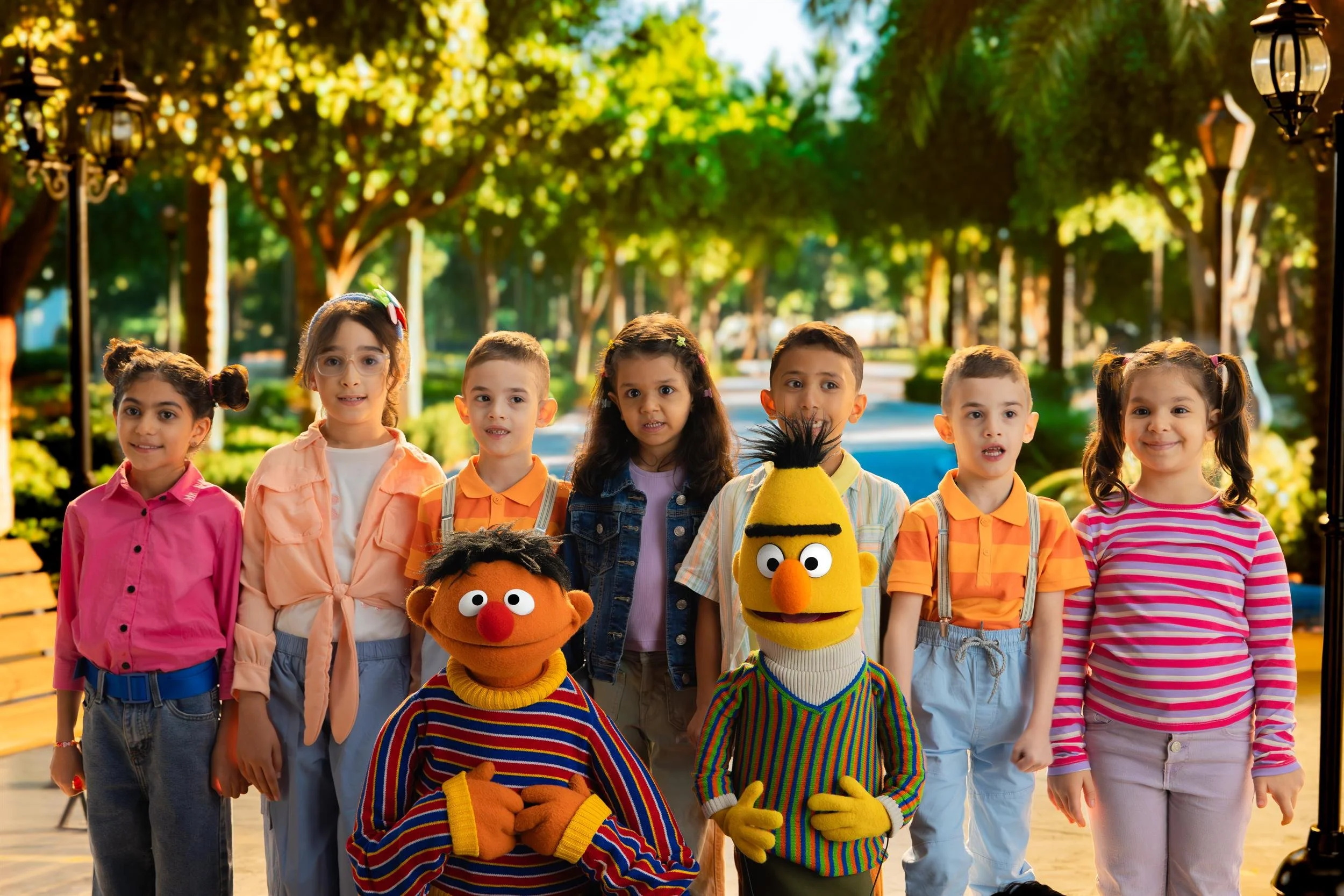 Ahlan Simsim key art: children line up beside Bert and another muppet on a park path.