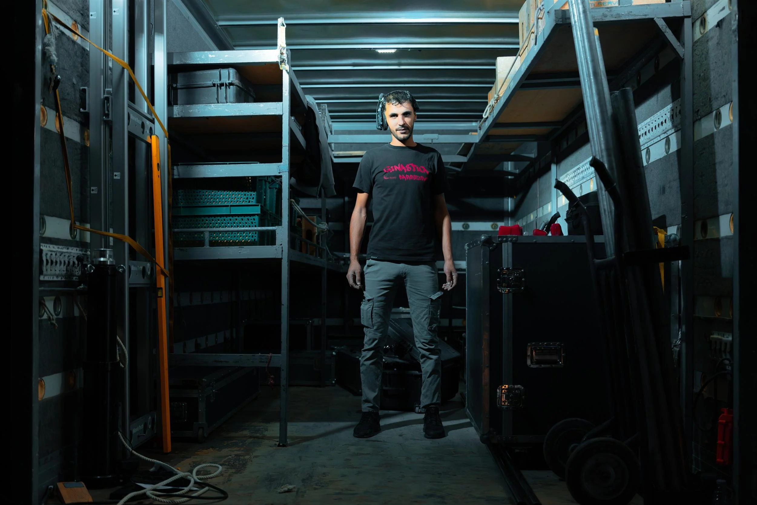 Ahlan Simsim unit still: A crew member wearing headphones stands inside a production equipment truck surrounded by gear.