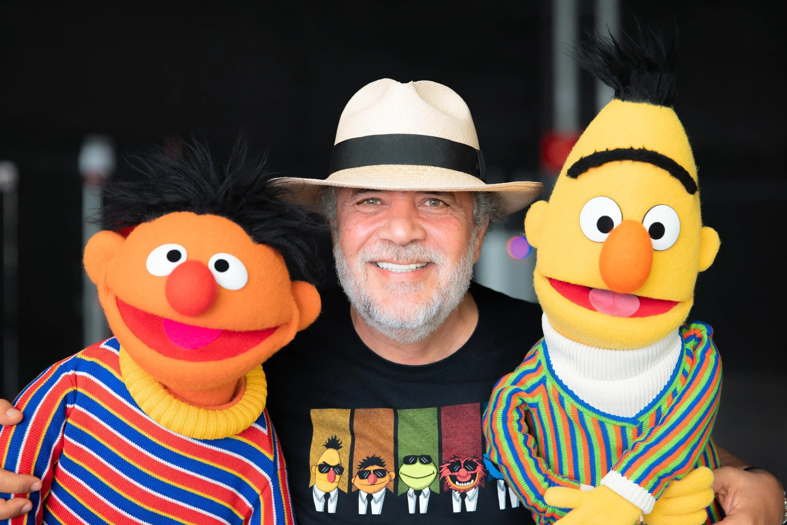 Ahlan Simsim unit still: a man in a fedora smiles while posing between Ernie and Bert.