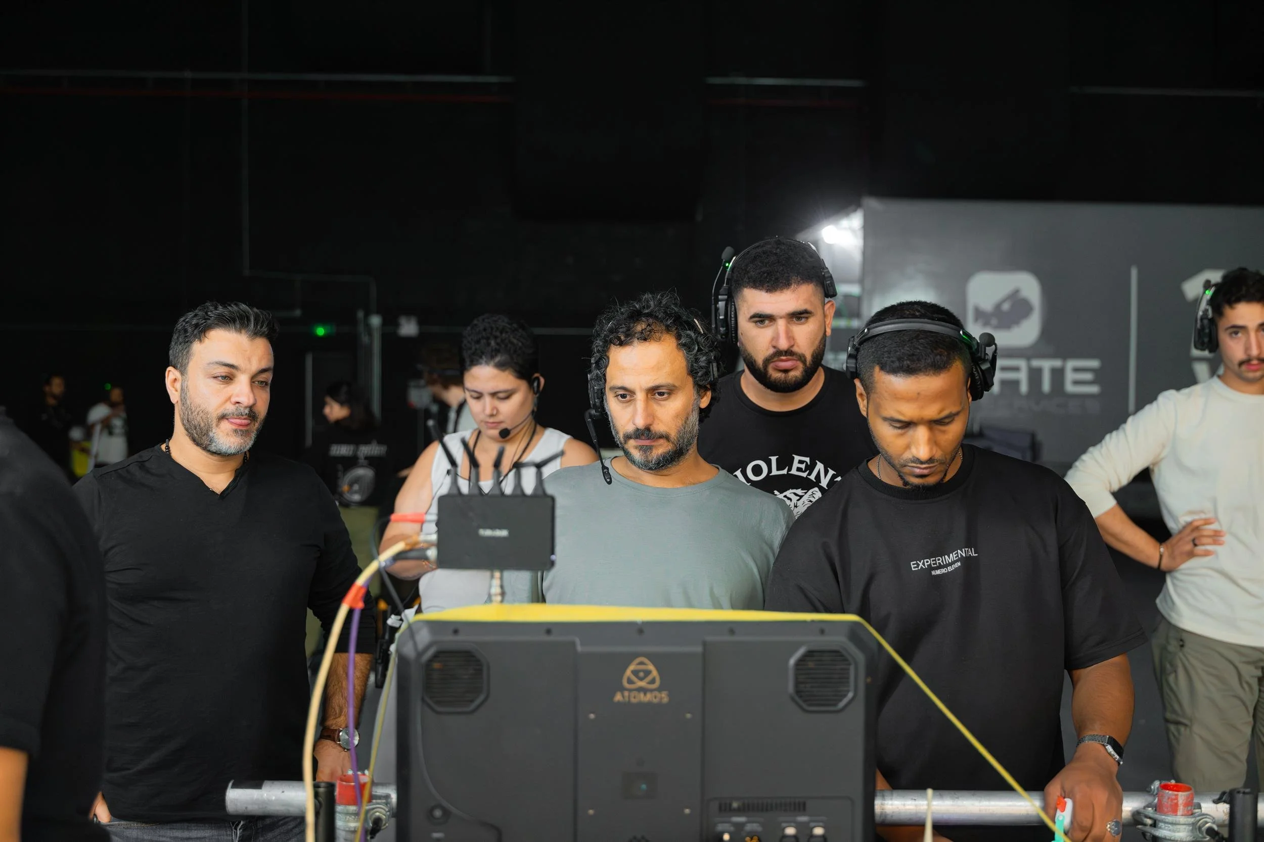 Ahlan Simsim unit still: Crew members wearing headsets gather around a production monitor in a studio.